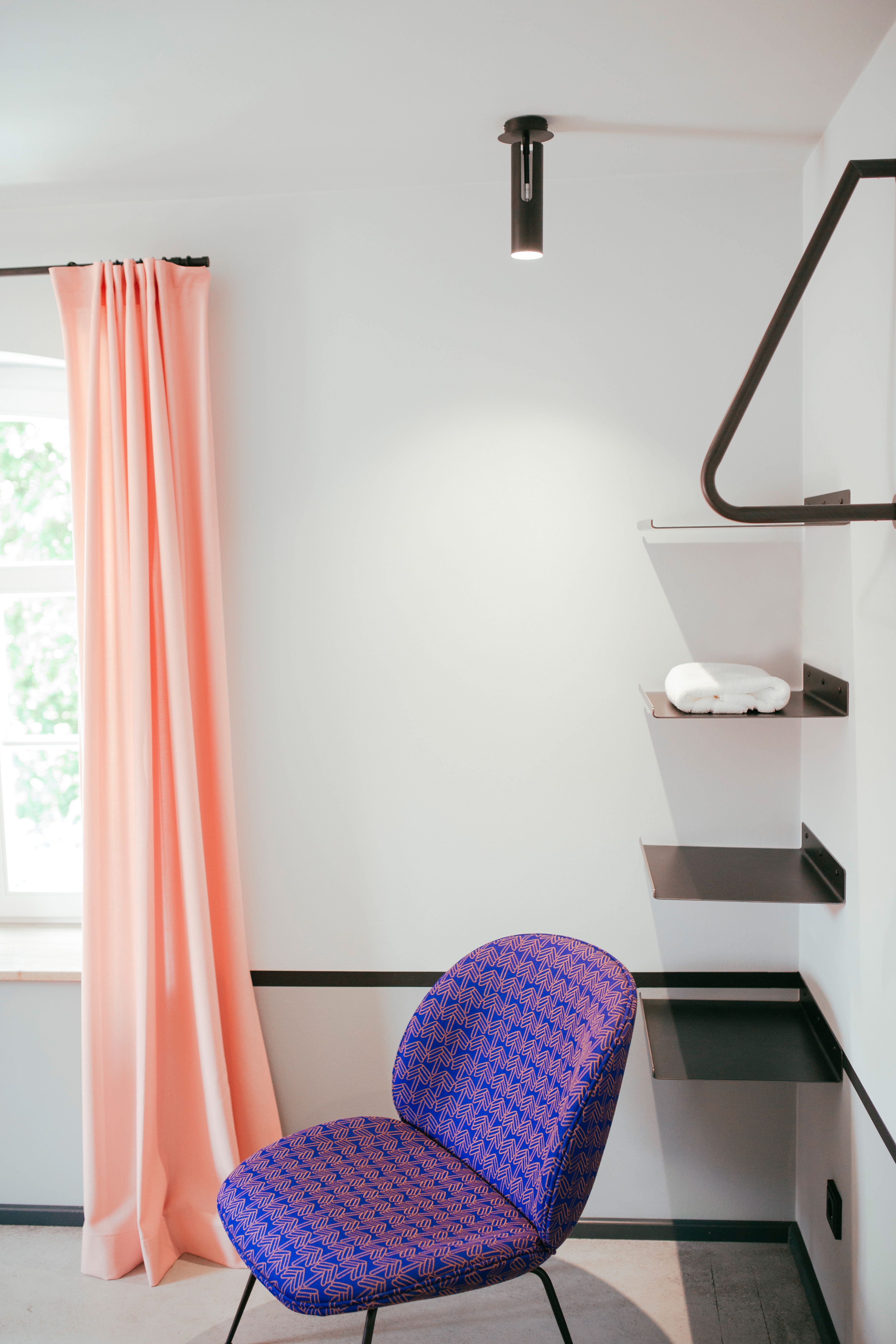 Der Arbeitsplatz mit farbigem Vorhang, grafischem Stuhl und reduzierter Möblierung zeigt das Interior Design von Stephanie Thatenhorst im Hotel Kloster Möllenbeck.