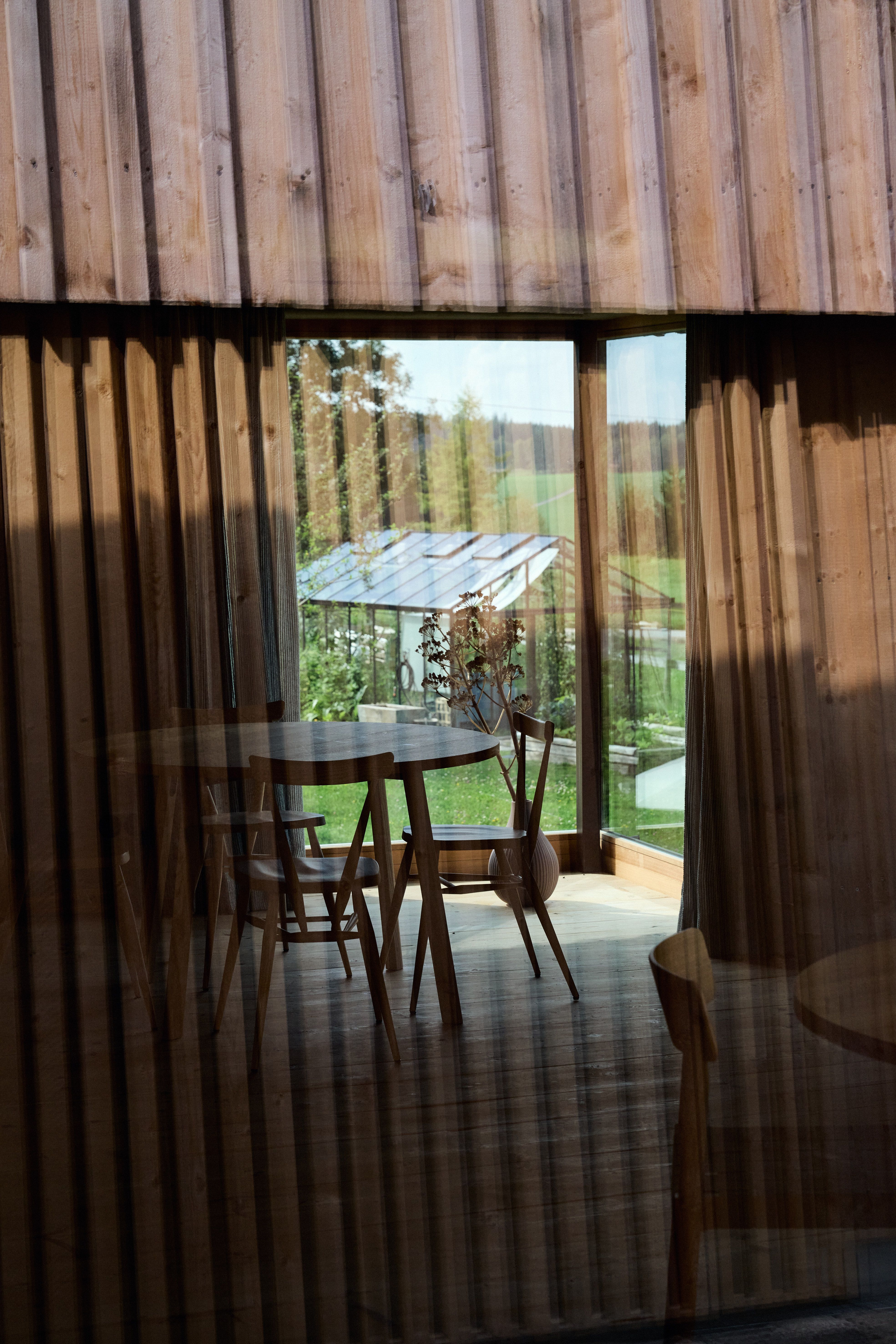 Architektonische Fassadenstruktur mit Blick in den hellen Essbereich als harmonisches Übergangsspiel von Innen und Außen, gestaltet von Stephanie Thatenhorst.