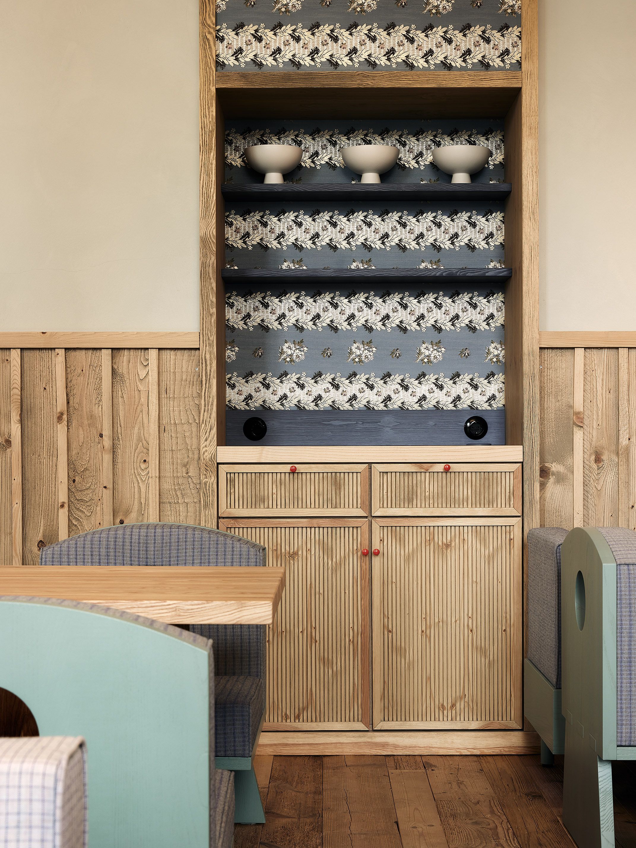 Eine maßgeschneiderte Nische mit gemusterter Stoffbespannung und Keramikobjekten verleiht dem Raum Tiefe und wohnliche Eleganz.