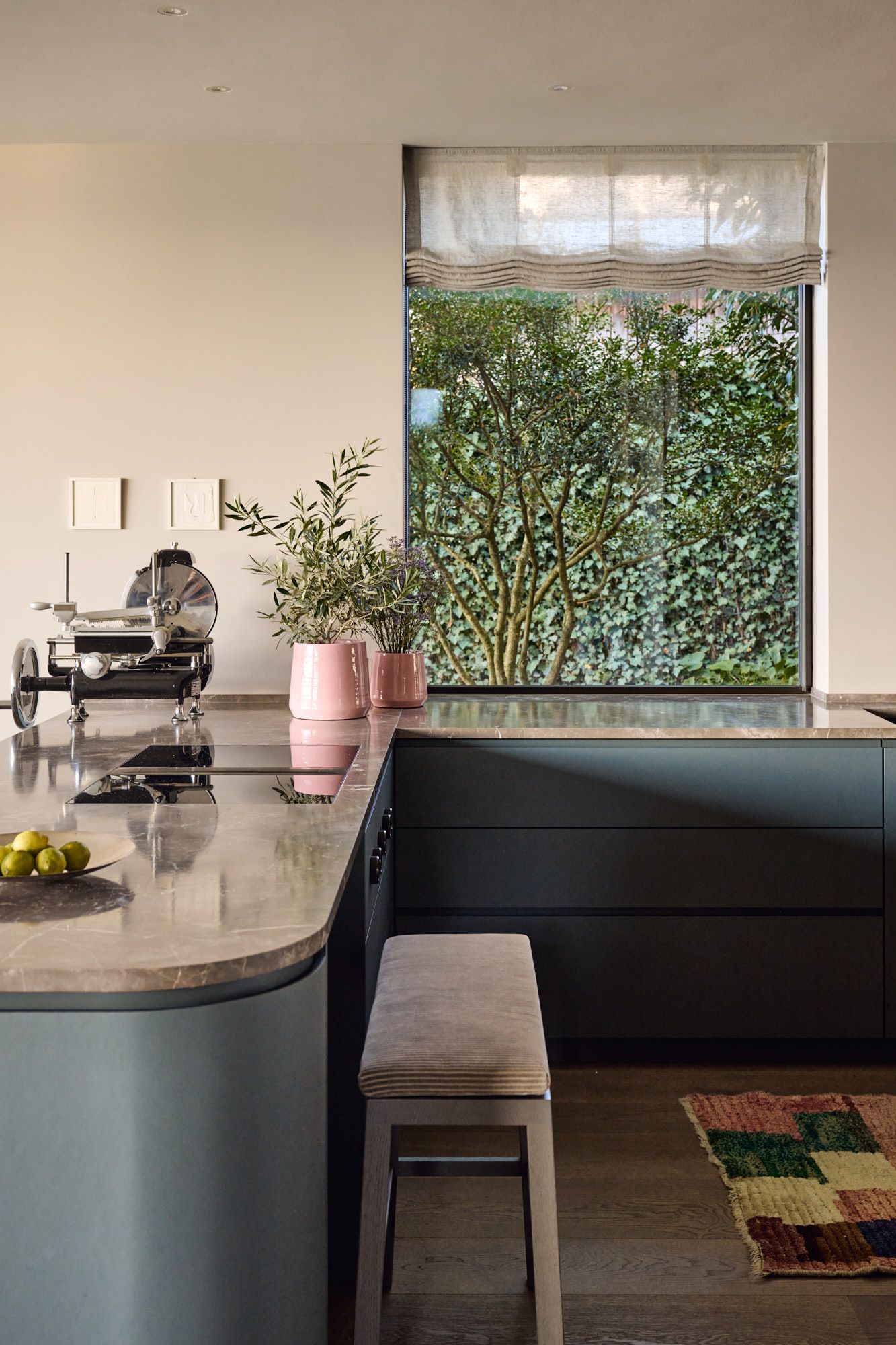 Helle Wohnküche mit sanften Naturtönen, abgerundeter Steinplatte und Blick ins Grüne für ein harmonisch modernes Ambiente.