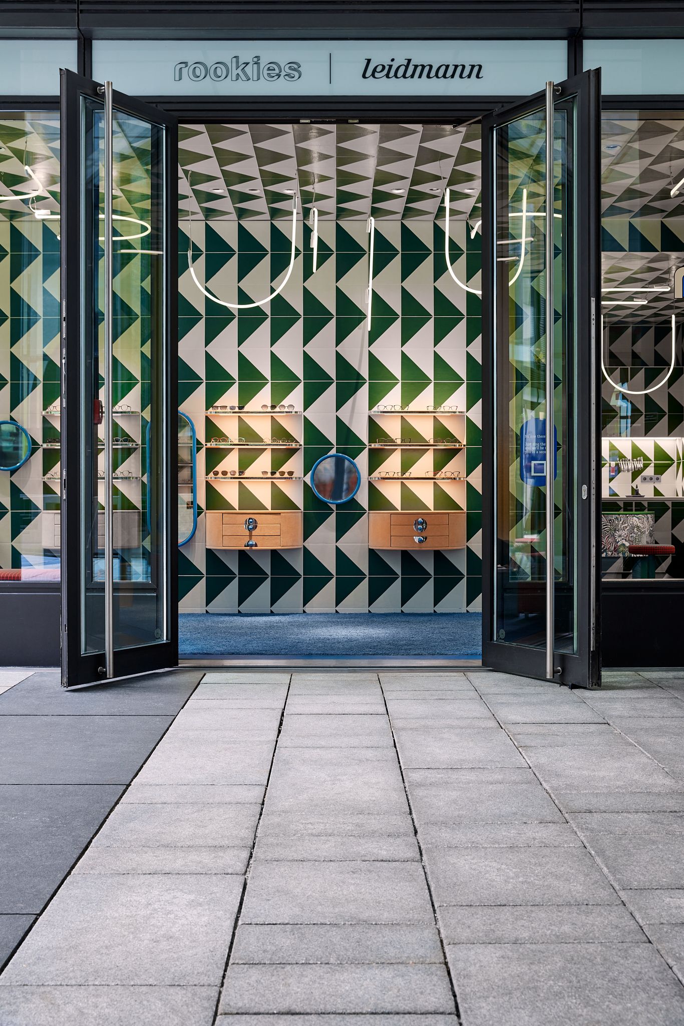 Die offene Ladenfront gibt den Blick frei auf das ausdrucksstarke geometrische Wandmuster und die hochwertige Produktpräsentation – designt von Stephanie Thatenhorst für Rookies Eyewear for Kids.