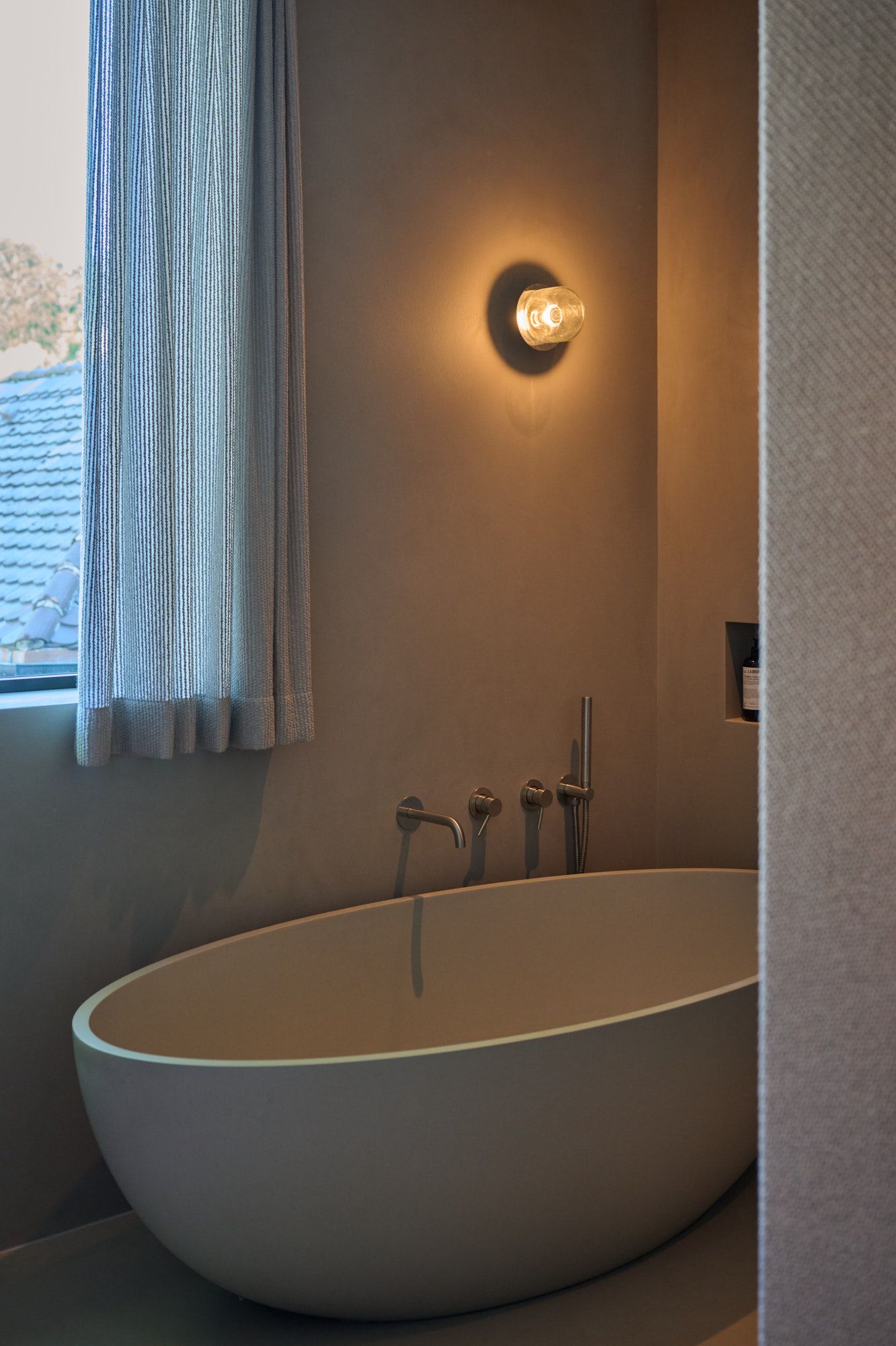 Zeitloses Badezimmer-Design von Stephanie Thatenhorst mit sanfter Beleuchtung und moderner Freistehbadewanne