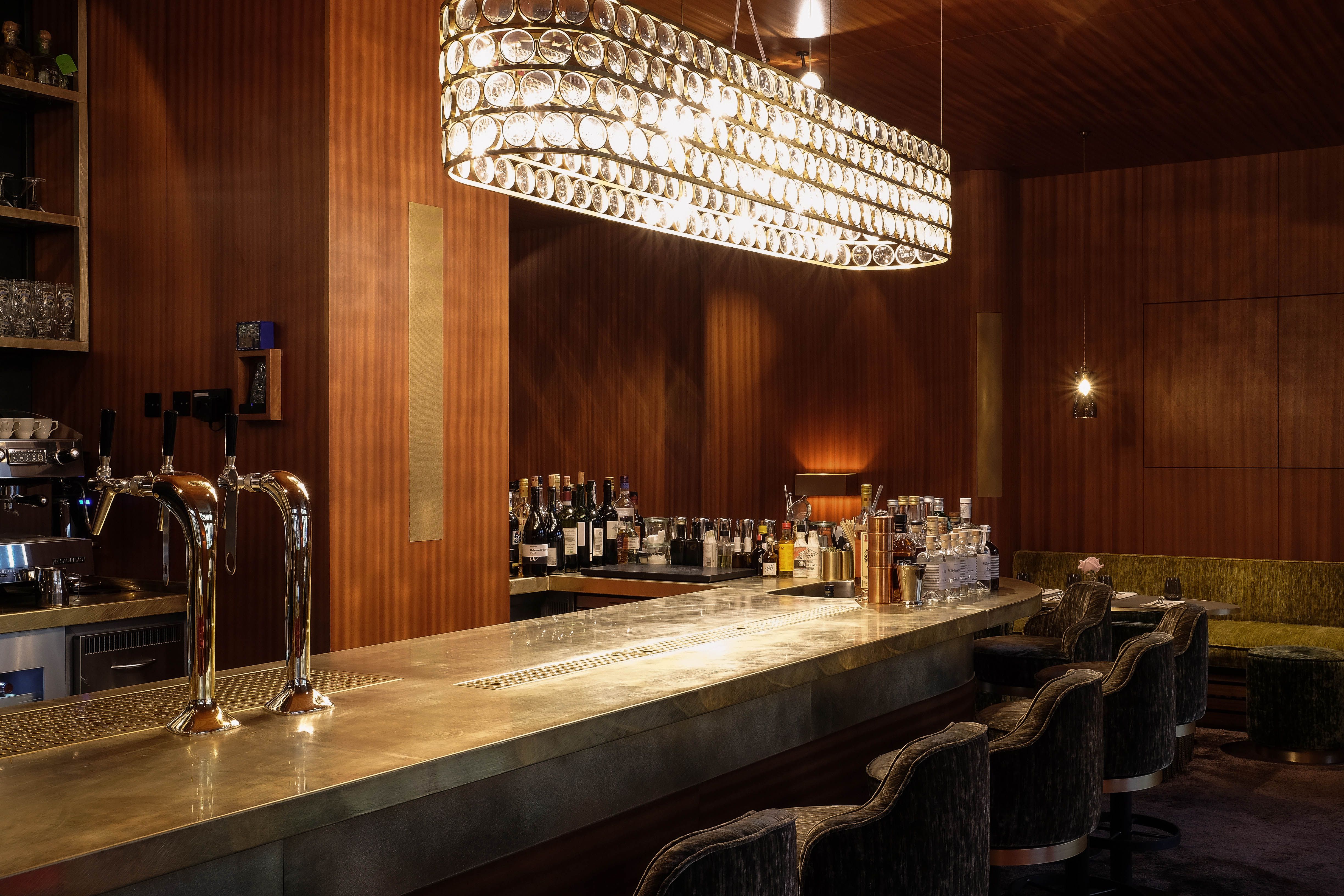 Der verglaste Weinschrank fungiert als elegantes Bindeglied zwischen Barbereich und Loungezone.