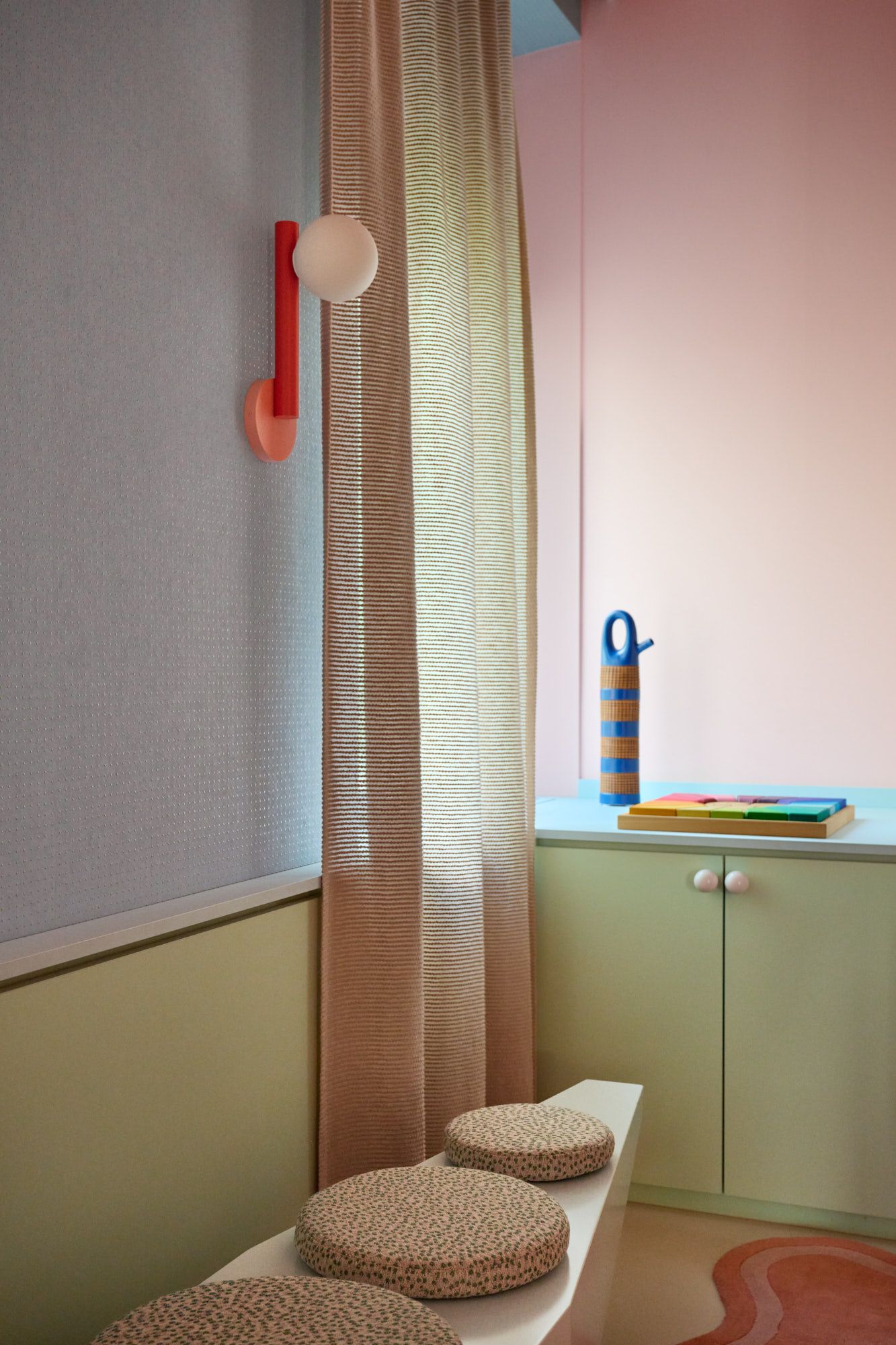 Verspielt gestalteter Kinderraum mit farbenfrohen Designlampen, weichen Sitzmöbeln und harmonischer Pastellgestaltung für eine kreative und einladende Lern- und Spielumgebung.