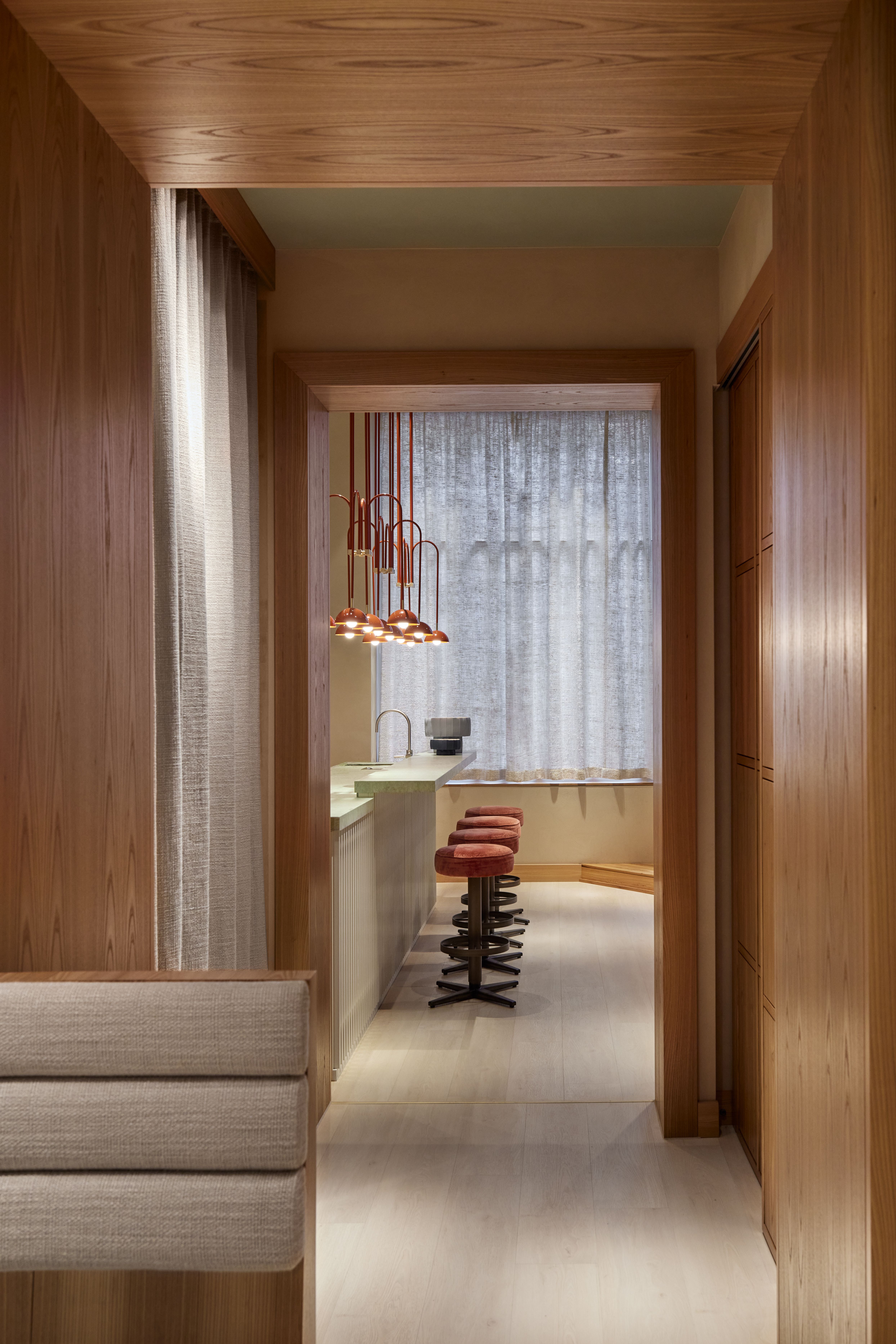 Eleganter Blick in das KOMU 2-Sterne-Restaurant, designt von Stephanie Thatenhorst, mit holzgetäfelten Nischen und sanften Lichtkörpern.