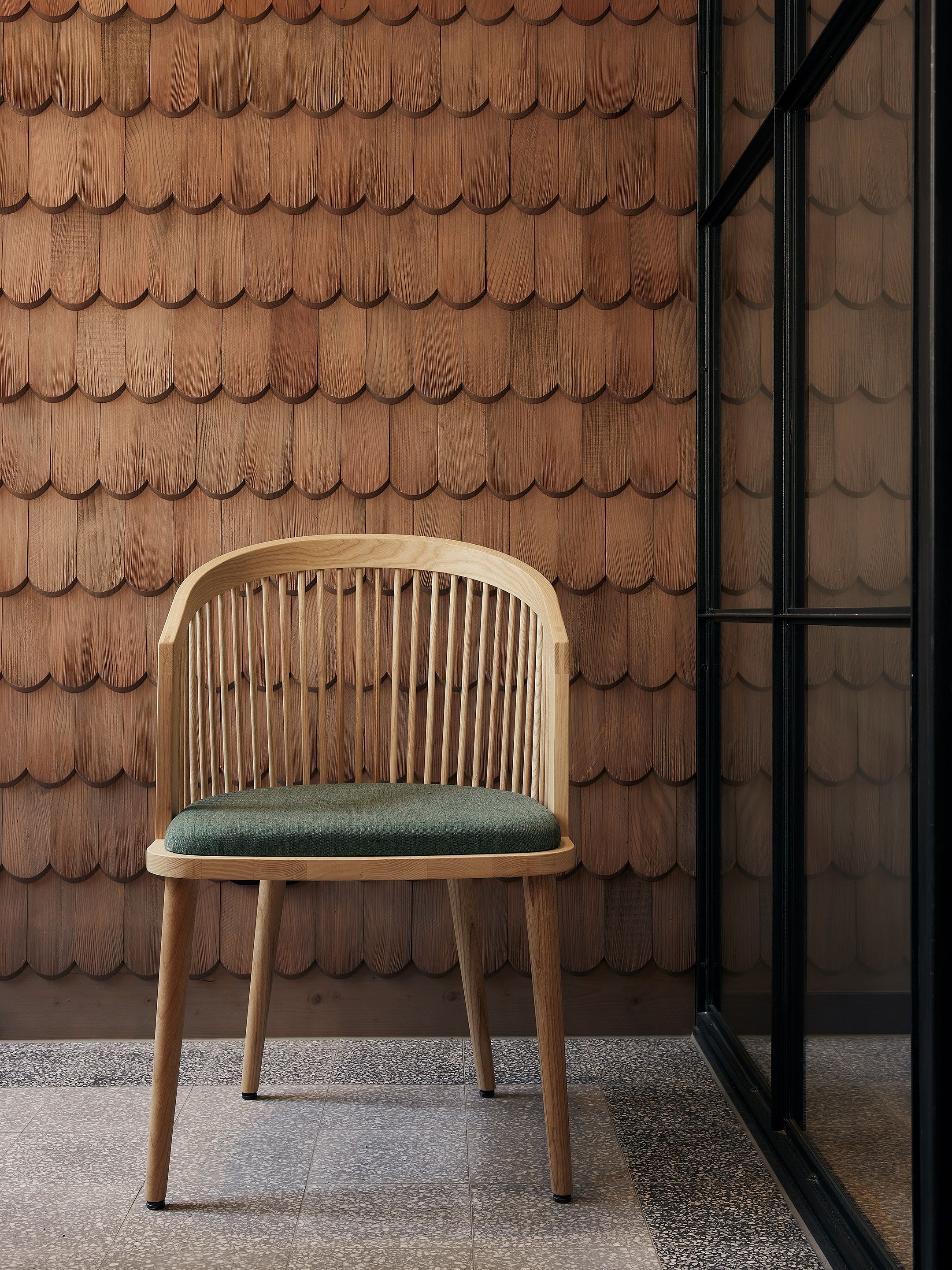 Die strukturierte Holzschindelwand setzt einen handwerklichen Akzent und betont das alpine Designkonzept des Benediktiner Weissbräuhaus.