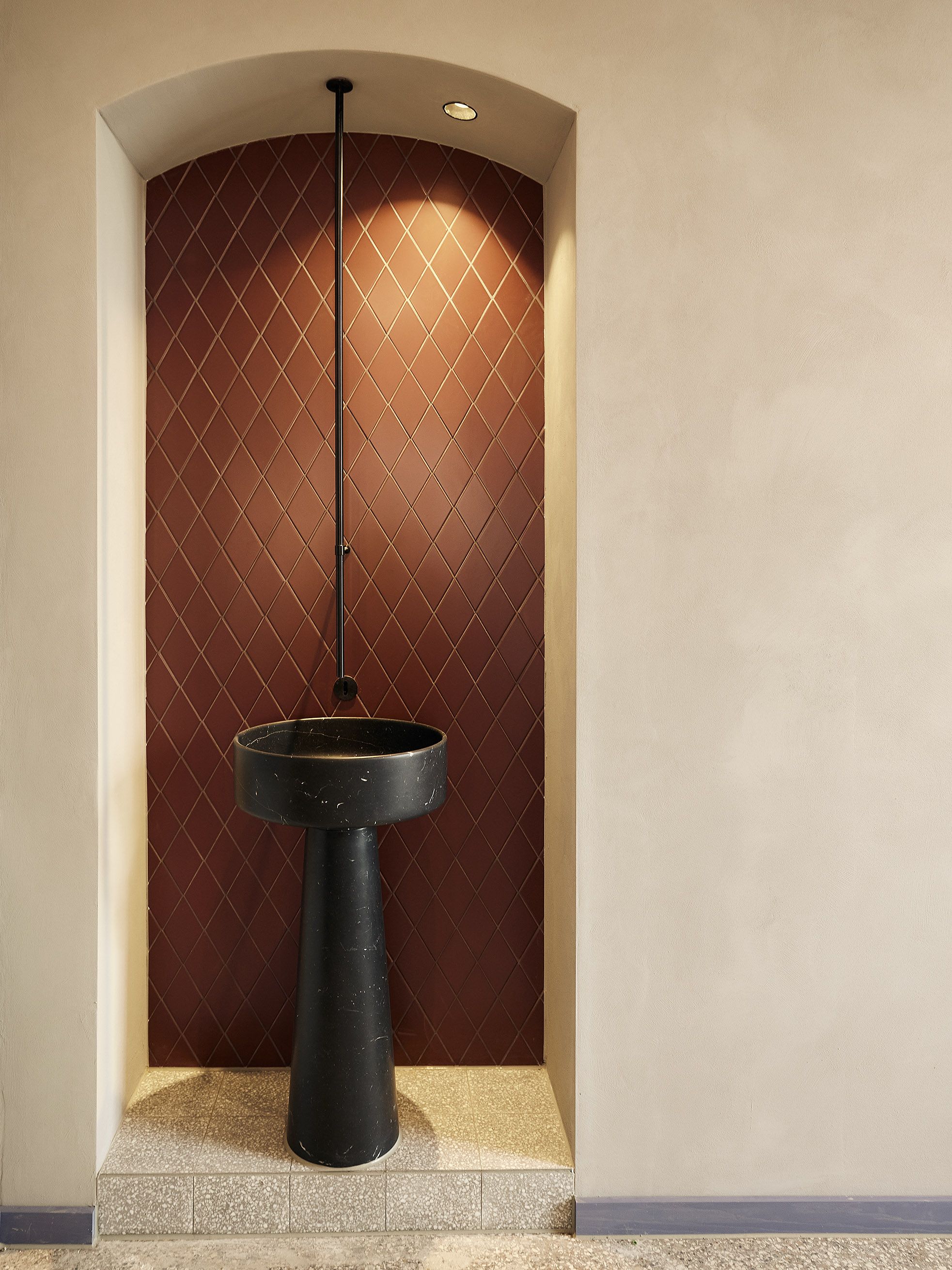 Der stilvoll inszenierte Waschplatz mit schwarzem Natursteinbecken und terracottafarbenen Fliesen unterstreicht das klare, reduzierte Interior-Konzept.