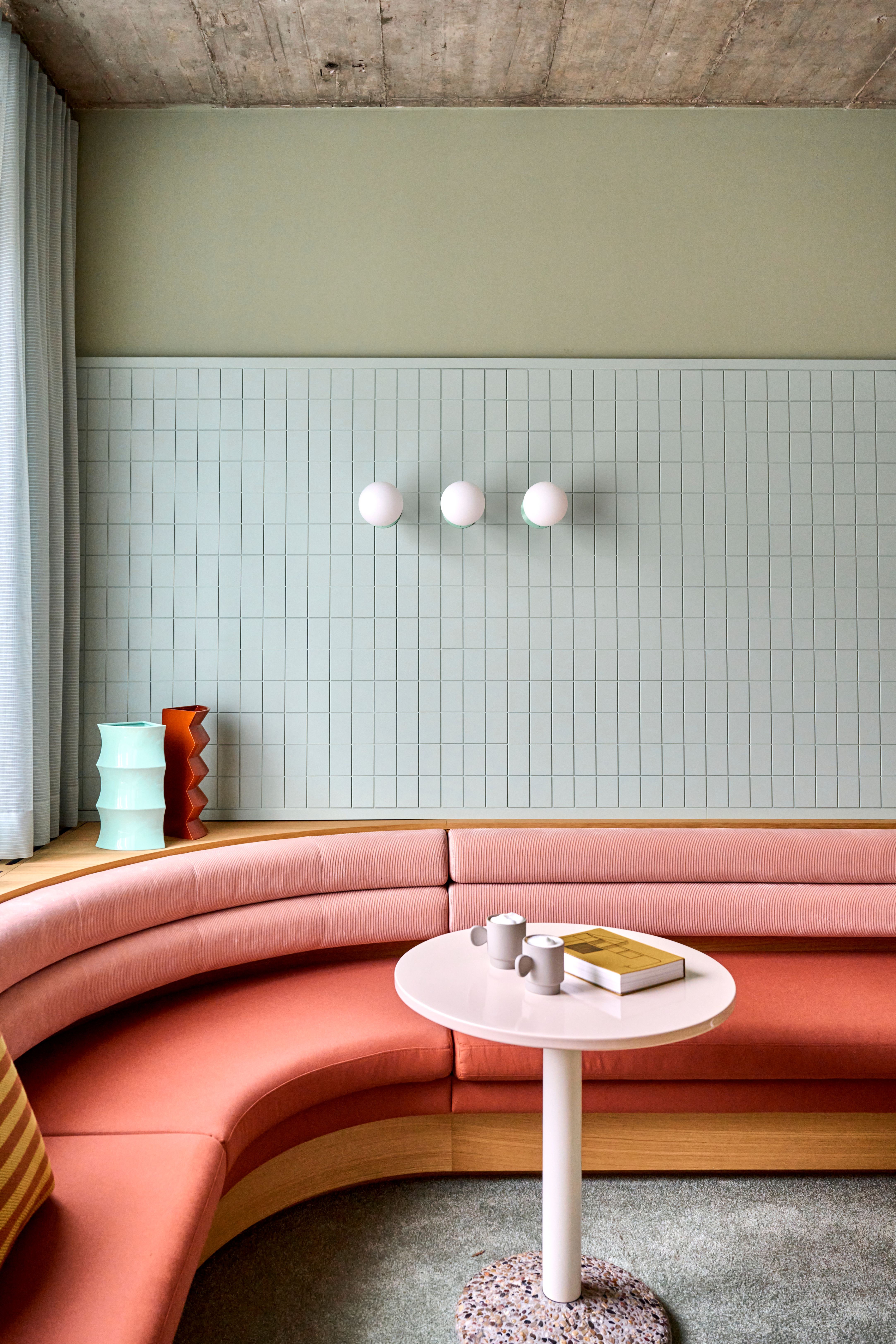 Die kurvige Sitzbank und pastellfarbene Wandgestaltung schaffen ein einladendes, wohnliches Raumgefühl für Patienten in der Praxiseinrichtung von Stephanie Thatenhorst.