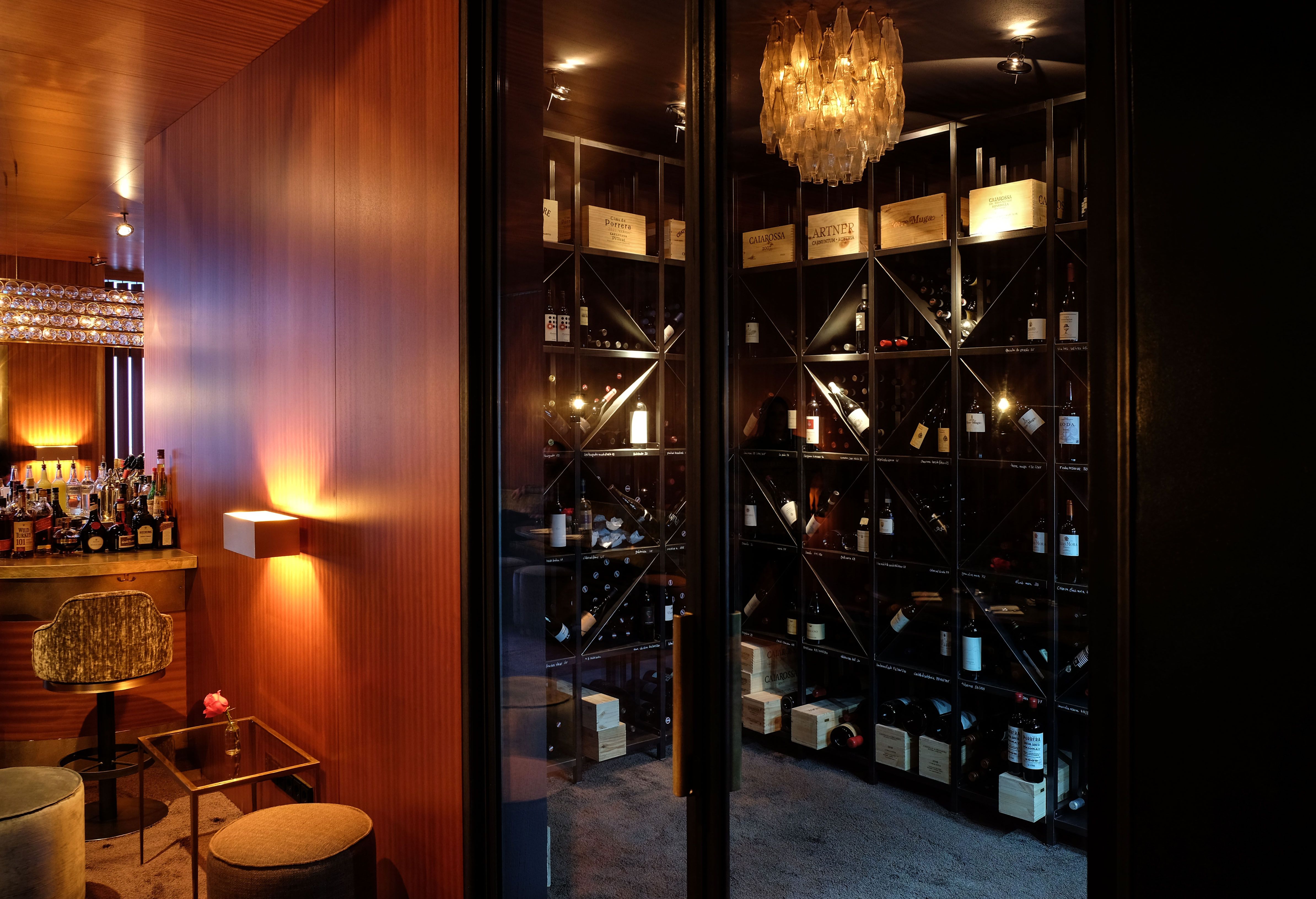 Der Übergang von Bar zu Sitzbereichen wird durch gezielte Beleuchtung und rhythmische Wandgliederung architektonisch betont.
