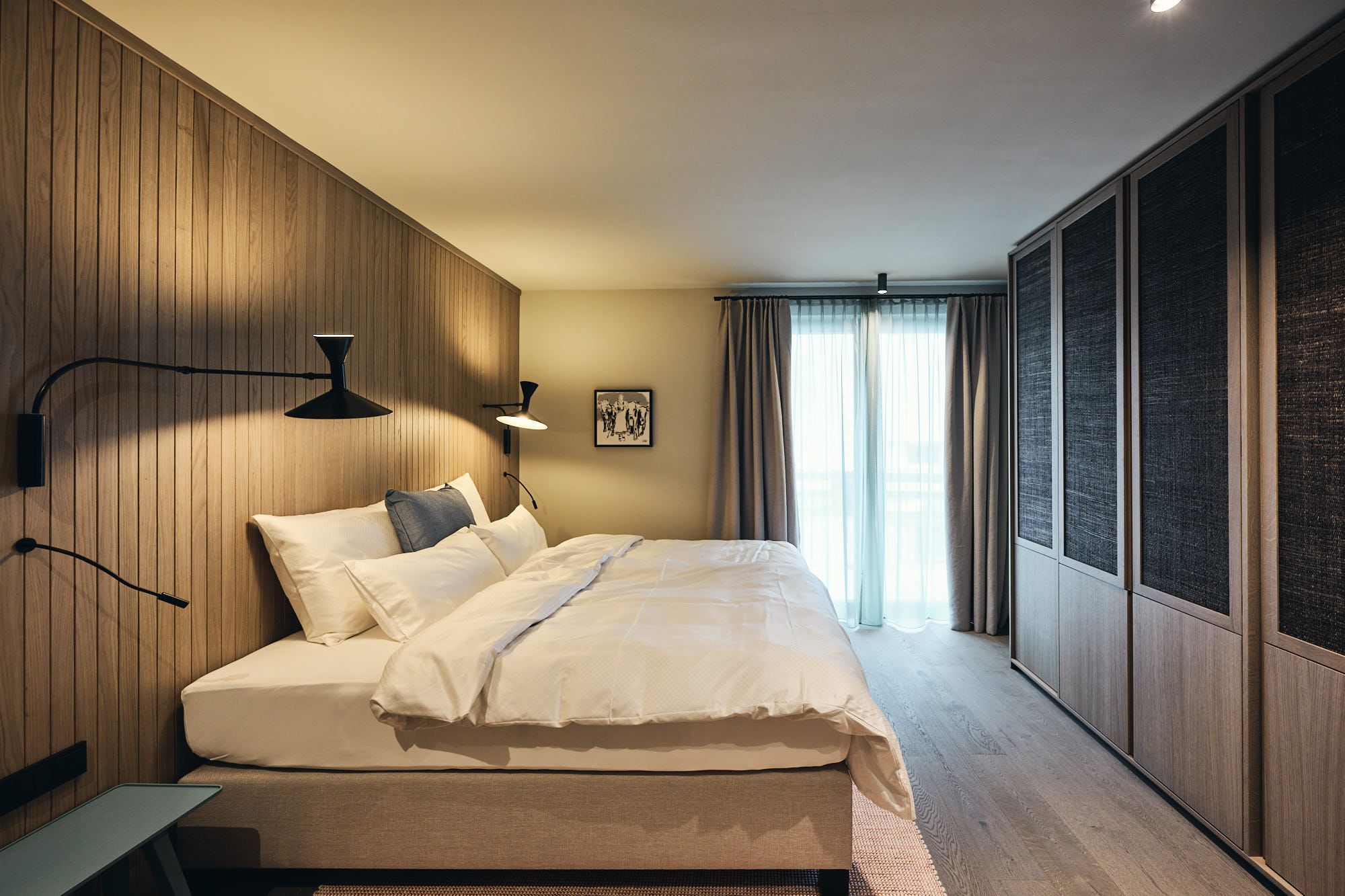 Das Schlafzimmer mit maßgefertigter Holzvertäfelung und sanfter Lichtstimmung reflektiert die ruhige Designphilosophie von Stephanie Thatenhorst im Ullrhaus.