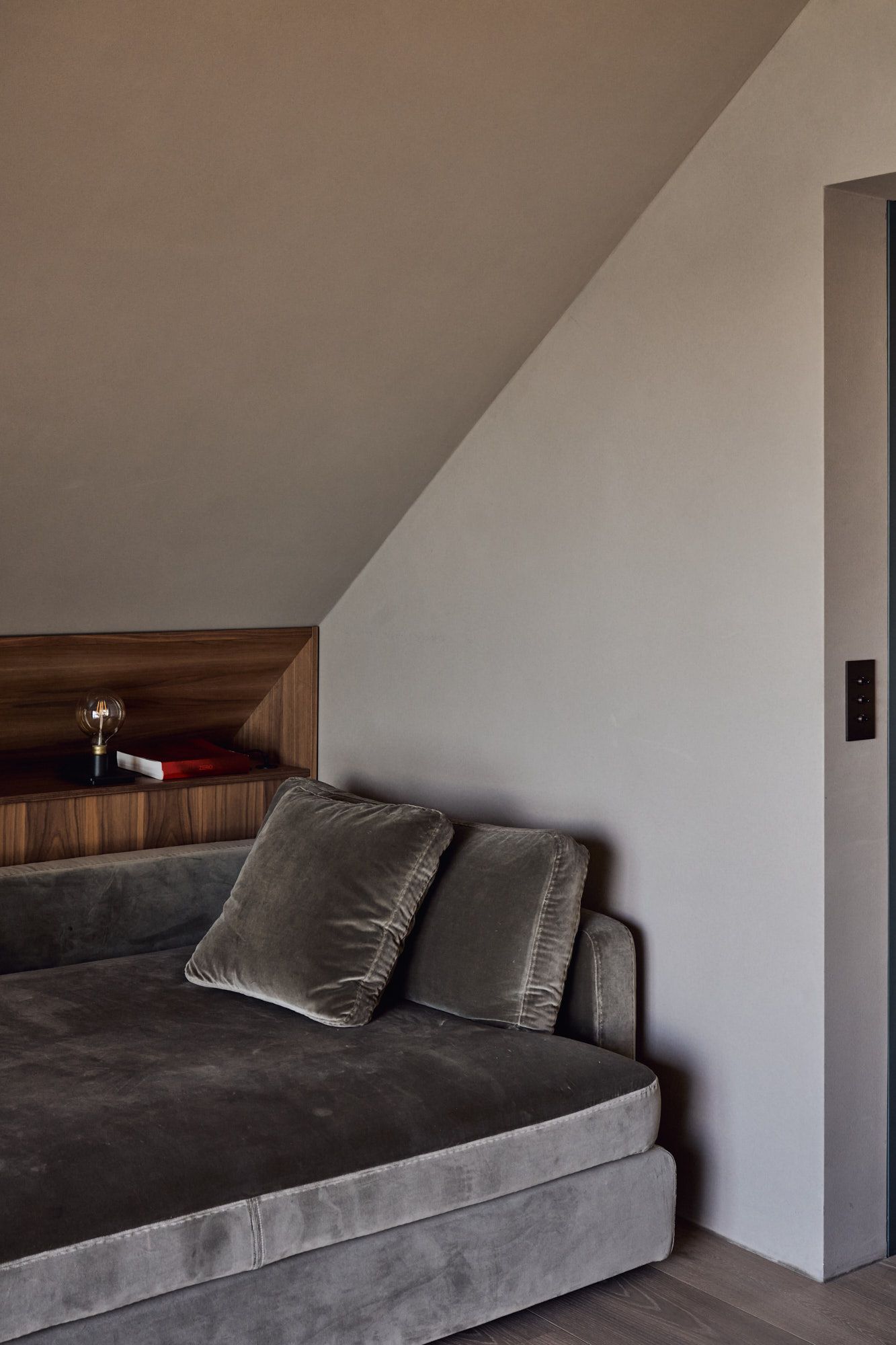 Gemütliche Schlafnische mit samtigem Polsterbett und integrierter Holzablage für eine elegante, ruhige Raumwirkung