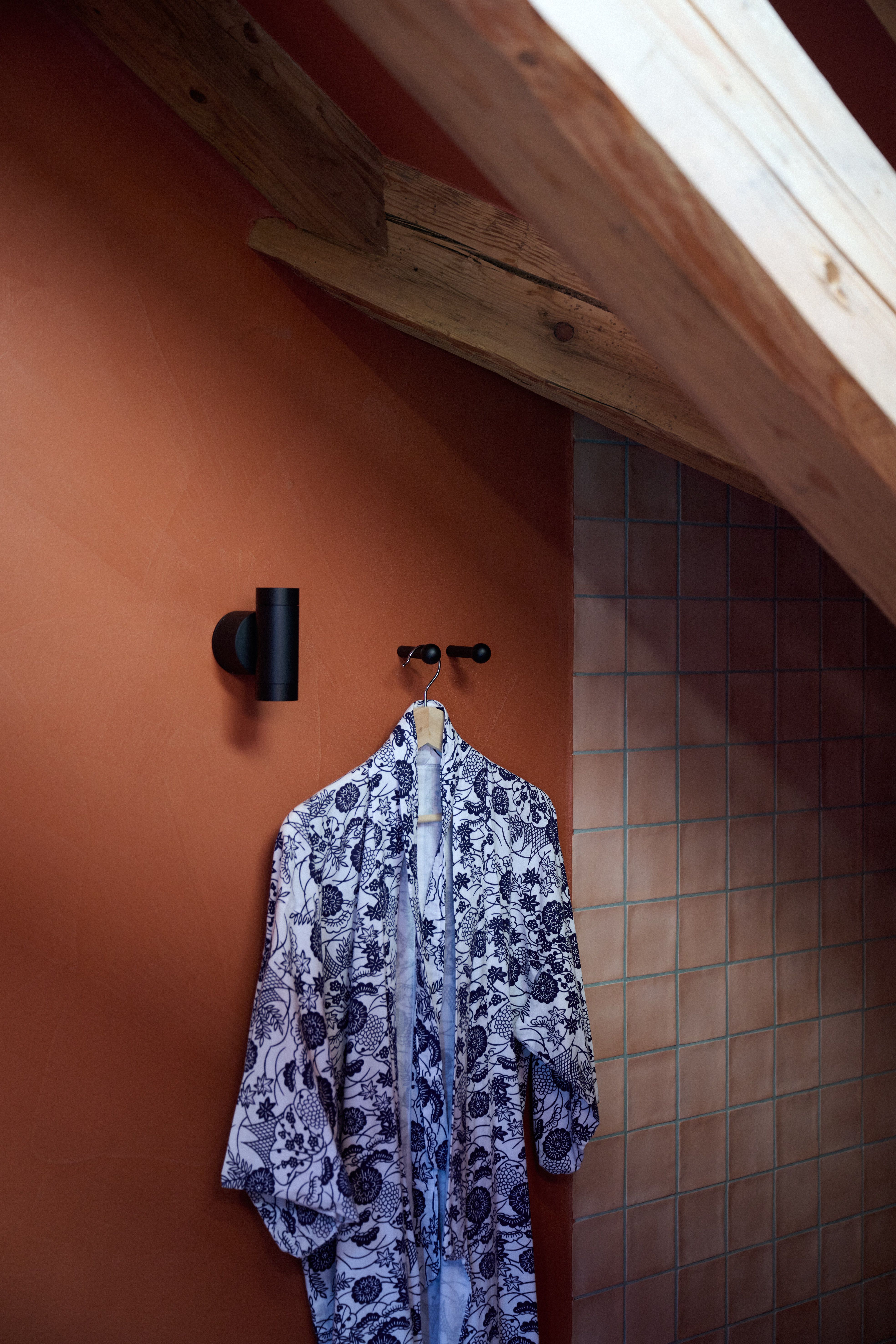 Warmtonige Badgestaltung mit Terrakotta-Putz und grafischem Kimono-Akzent, harmonisch umgesetzt von Stephanie Thatenhorst.