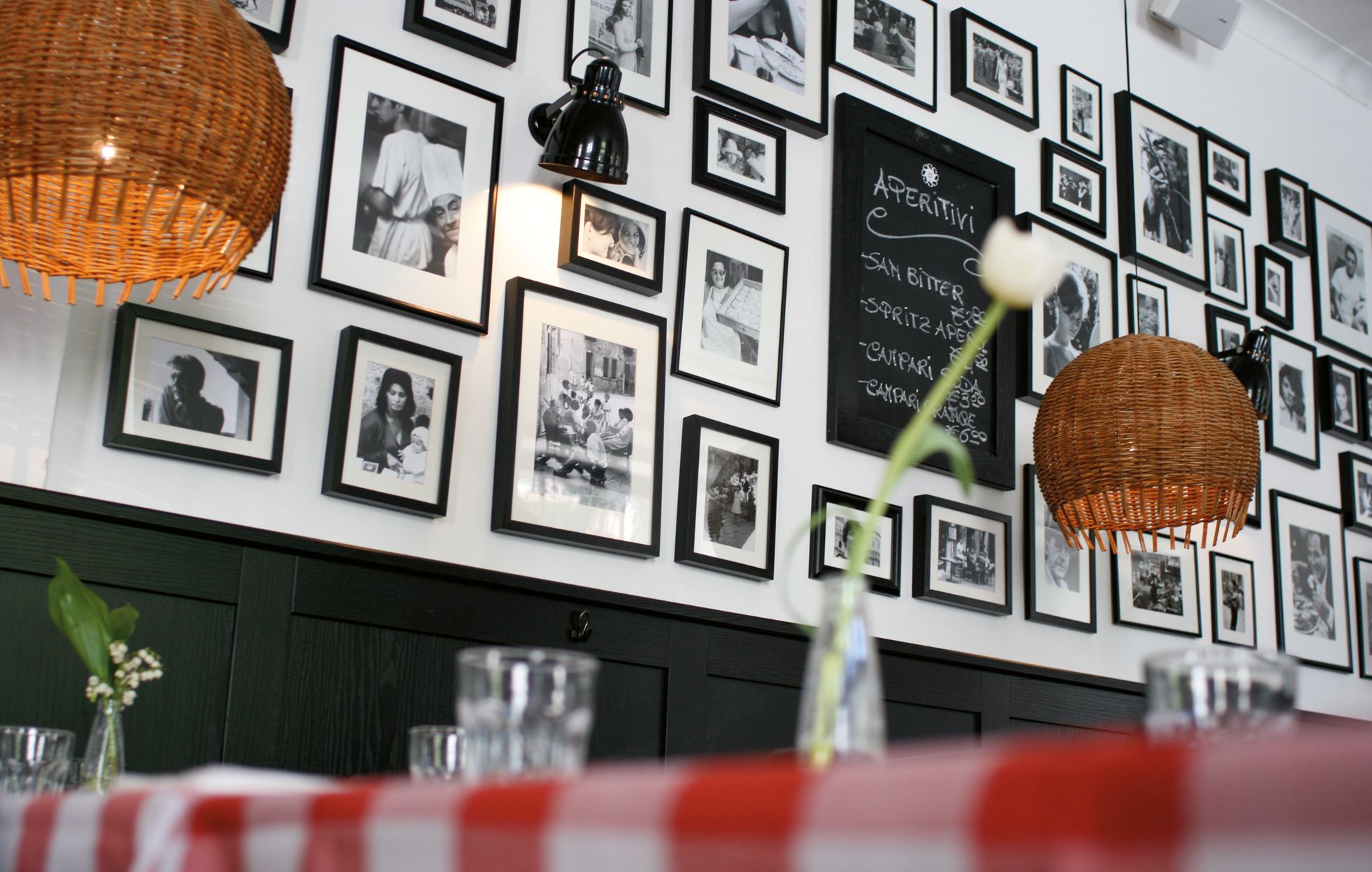 Die Bildwand mit historischen Fotografien erzählt visuell die kulinarische Herkunft und prägt den Charakter der Trattoria.