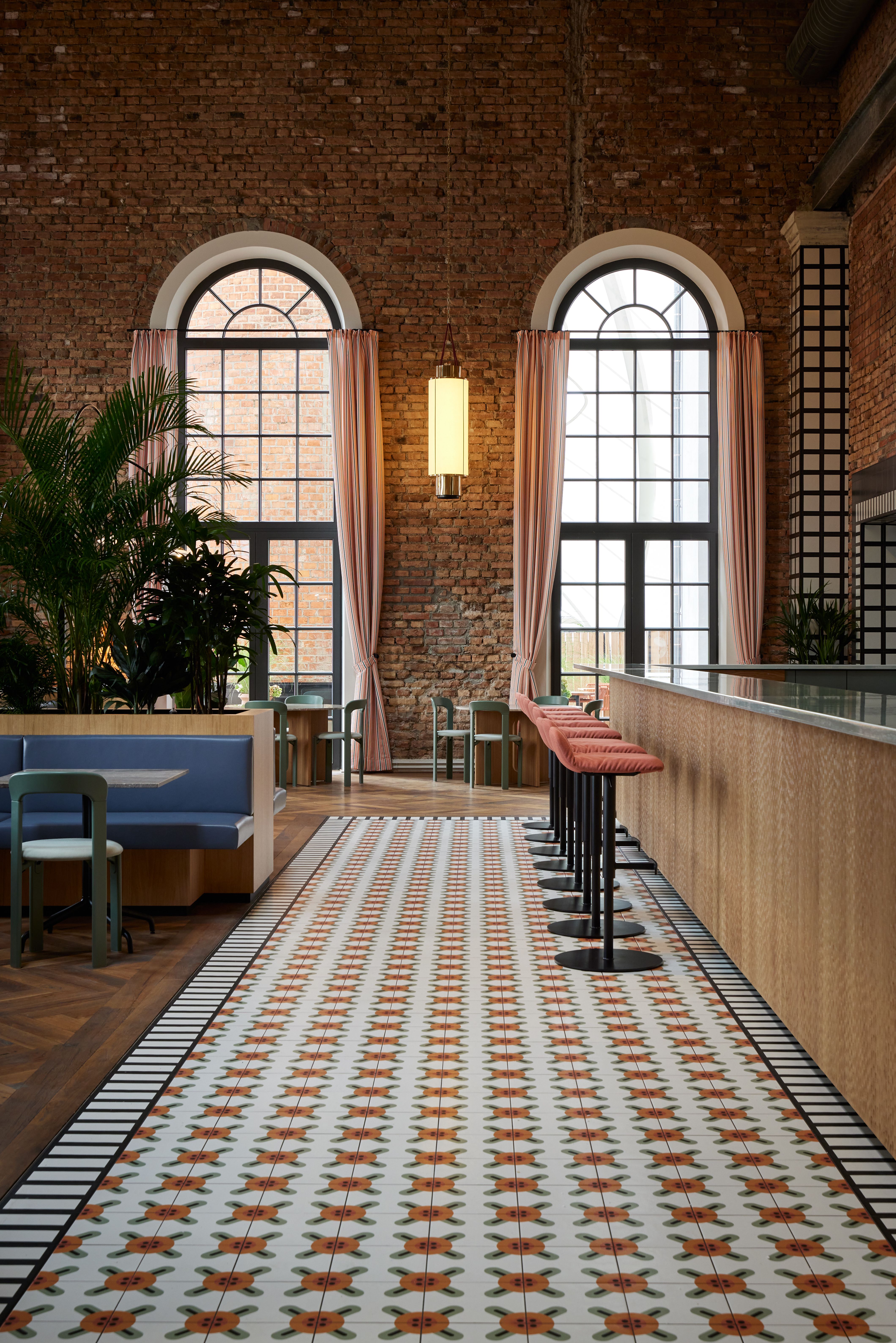 Die großzügige Fensterfront und die lineare Sitzbankgestaltung der Brasserie im Turbinenhaus Kolbermoor wurden von Stephanie Thatenhorst in weich getönten Pastellnuancen und architektonischem Vorhangfall umgesetzt.