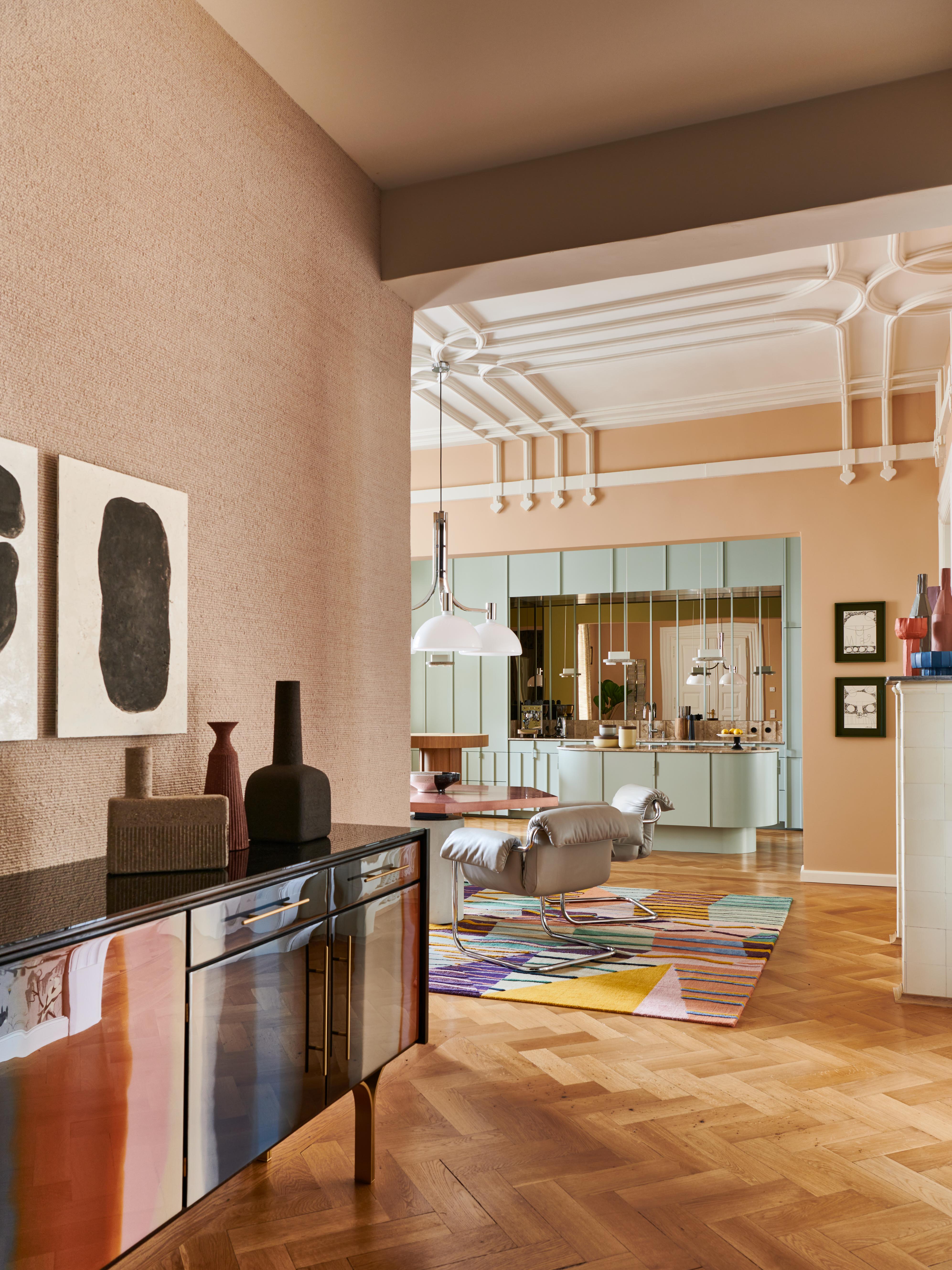 Ein kunstvoll inszenierter Showflat im Stephanie-Thatenhorst-Design mit farbintensivem Teppich, skulpturalen Objekten und einer eleganten, pastellfarbenen Küchenarchitektur zeigt ihre charakteristische Mischung aus Modernität, Wärme und kuratierter Designästhetik.