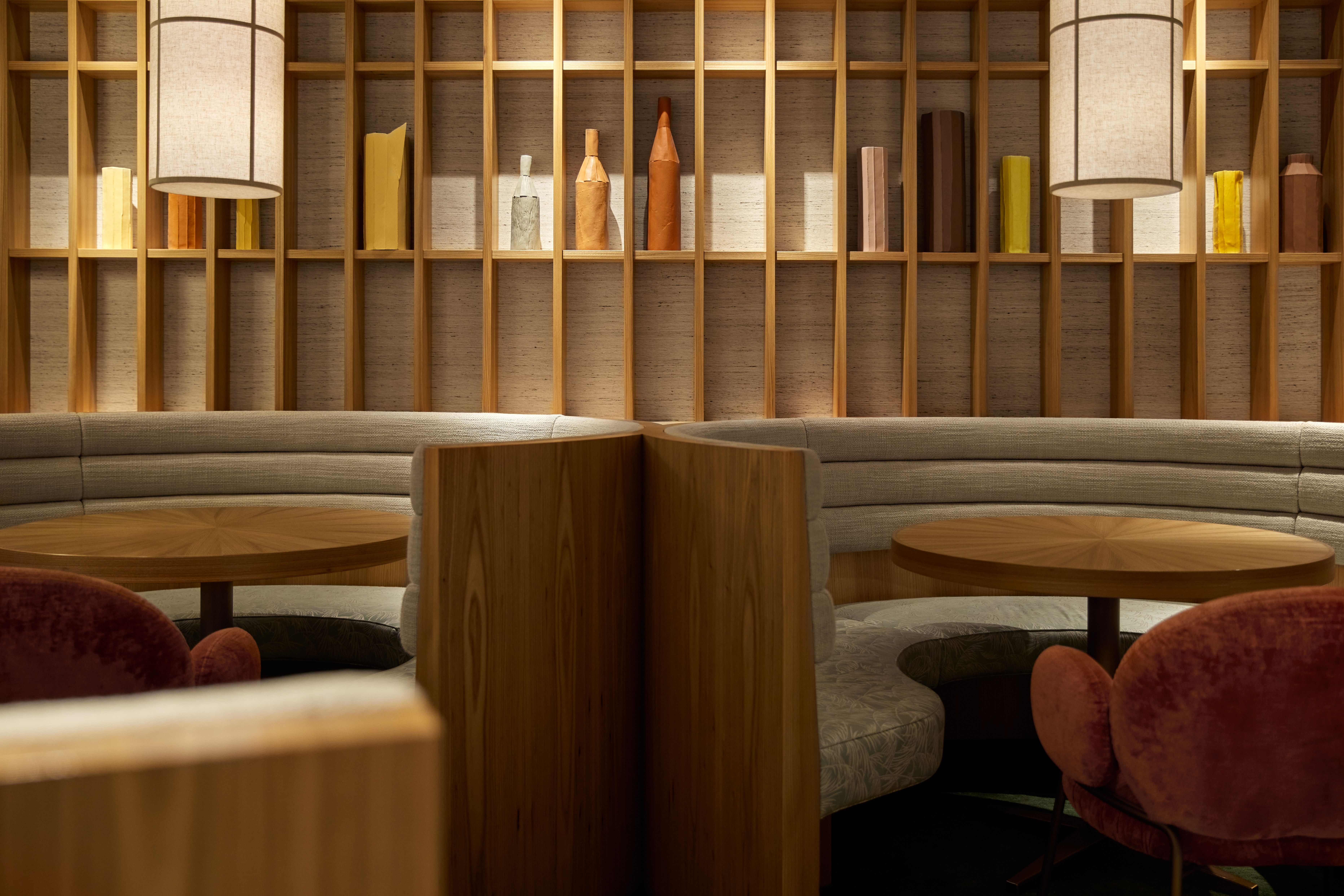 Pendelleuchte vor Holzregalsystem im KOMU 2-Sterne-Restaurant, entworfen von Stephanie Thatenhorst, als ikonisches Gestaltungselement.