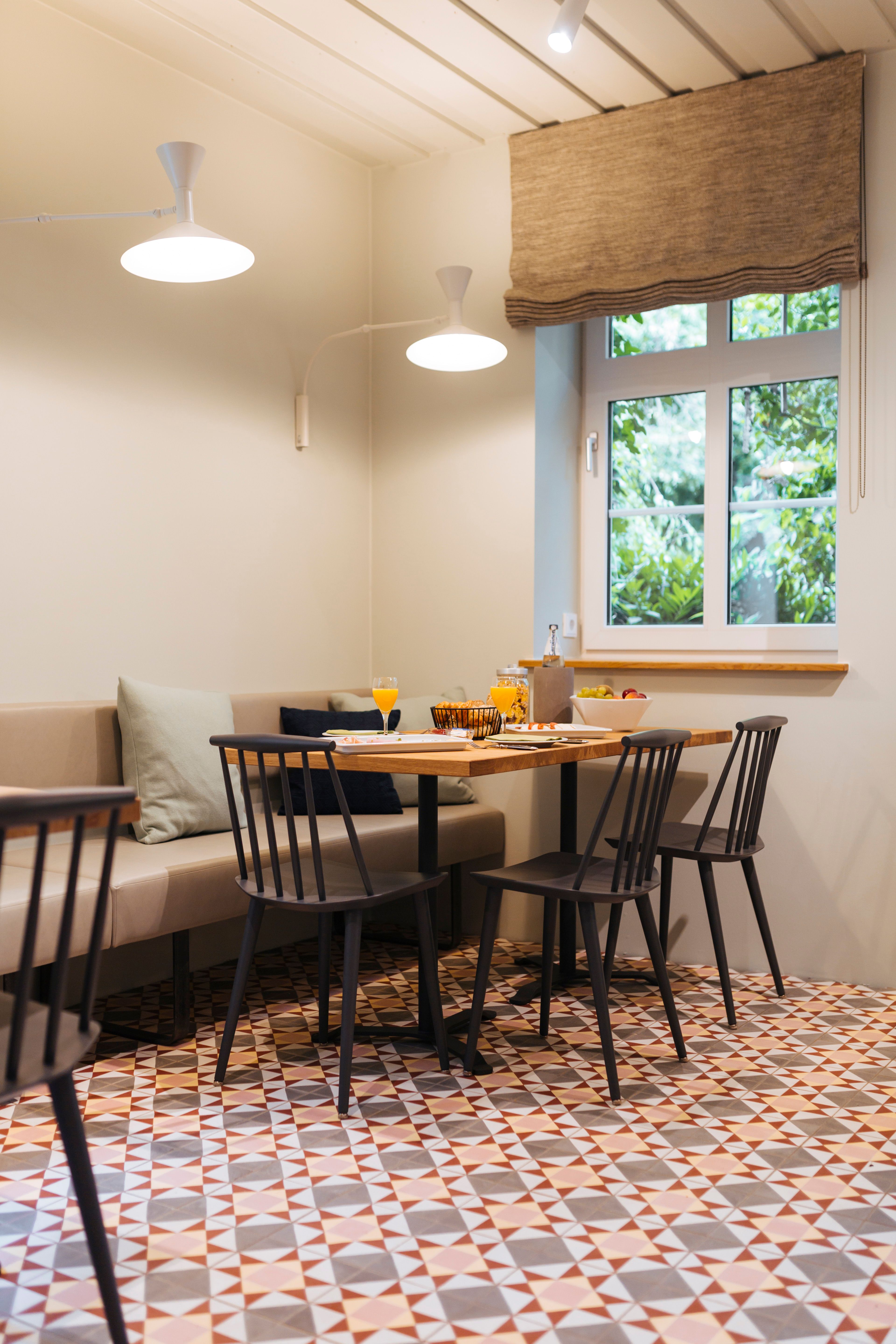 Der Frühstücks- und Aufenthaltsraum mit grafischem Boden, Holzmöbeln und Tageslicht gehört zum Interior Design des Hotels Kloster Möllenbeck von Stephanie Thatenhorst.