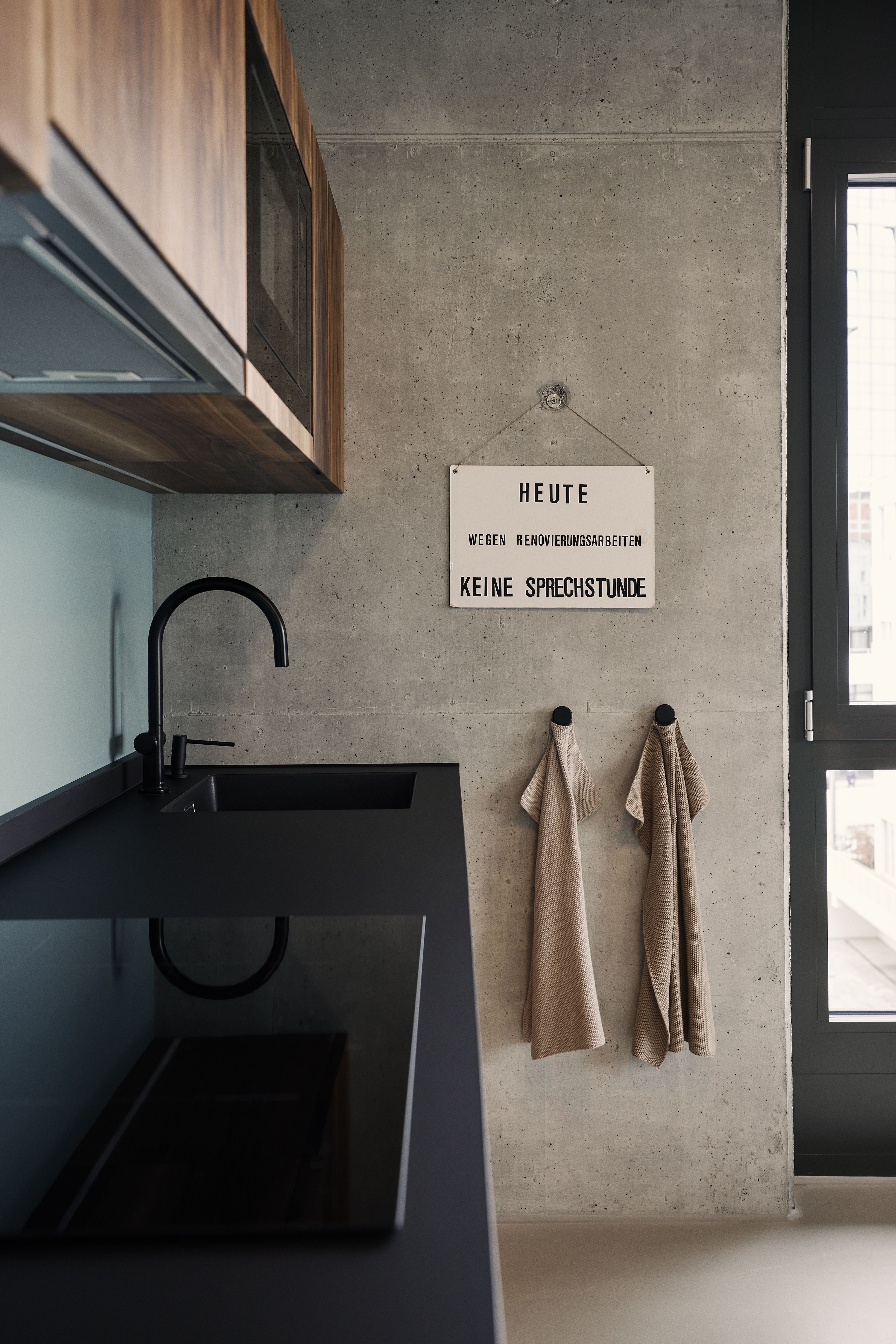 Die klar gestaltete Teeküche mit Sichtbeton und dunklen Armaturen zeigt das konsequent moderne Design der Zahnarztpraxis in Kempten.