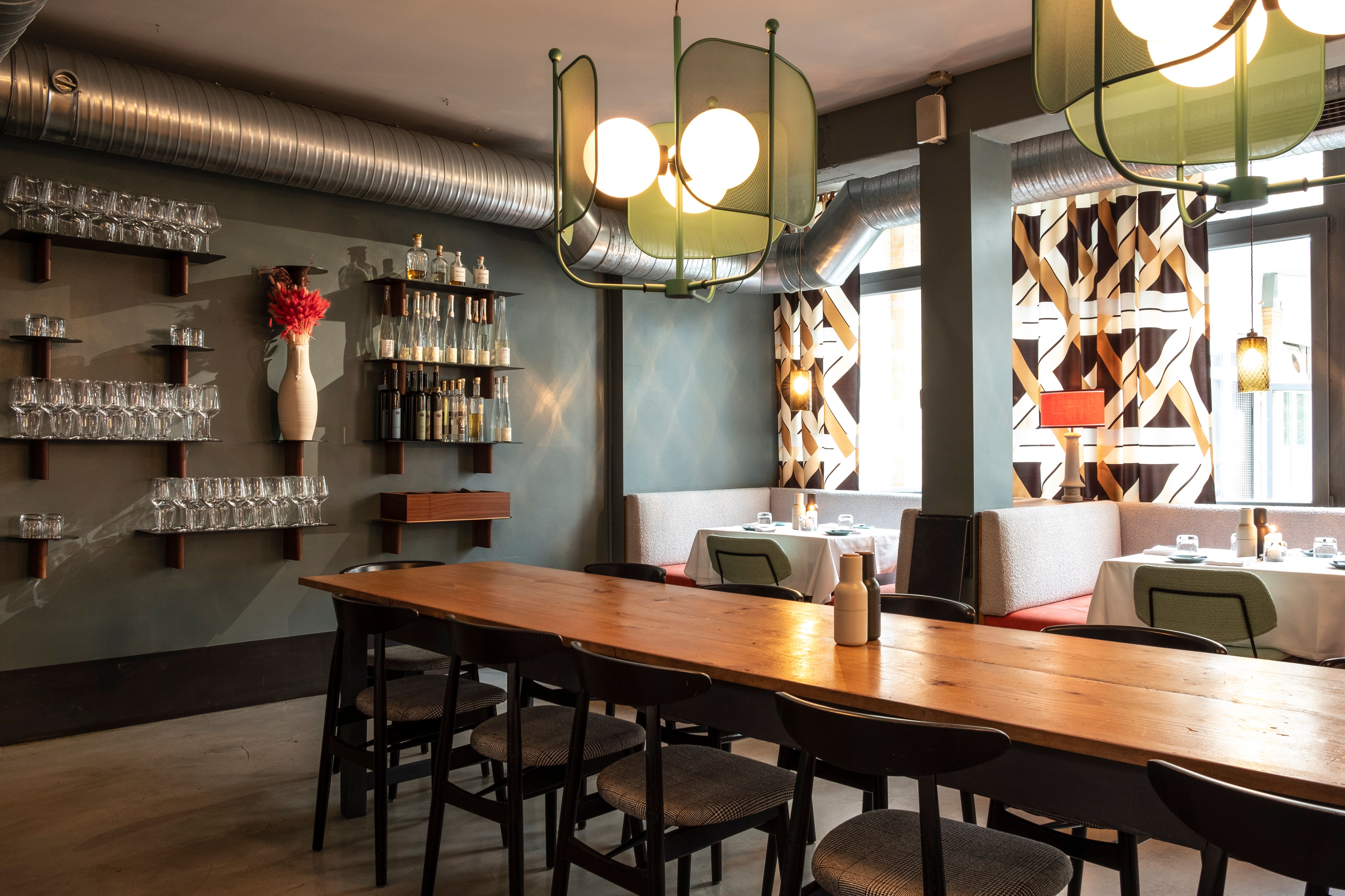 Der großzügige Gastraum des Theresa Grill Restaurants kombiniert industrielle Lüftungselemente mit eleganten Leuchten und hochwertiger Gastronomieeinrichtung.