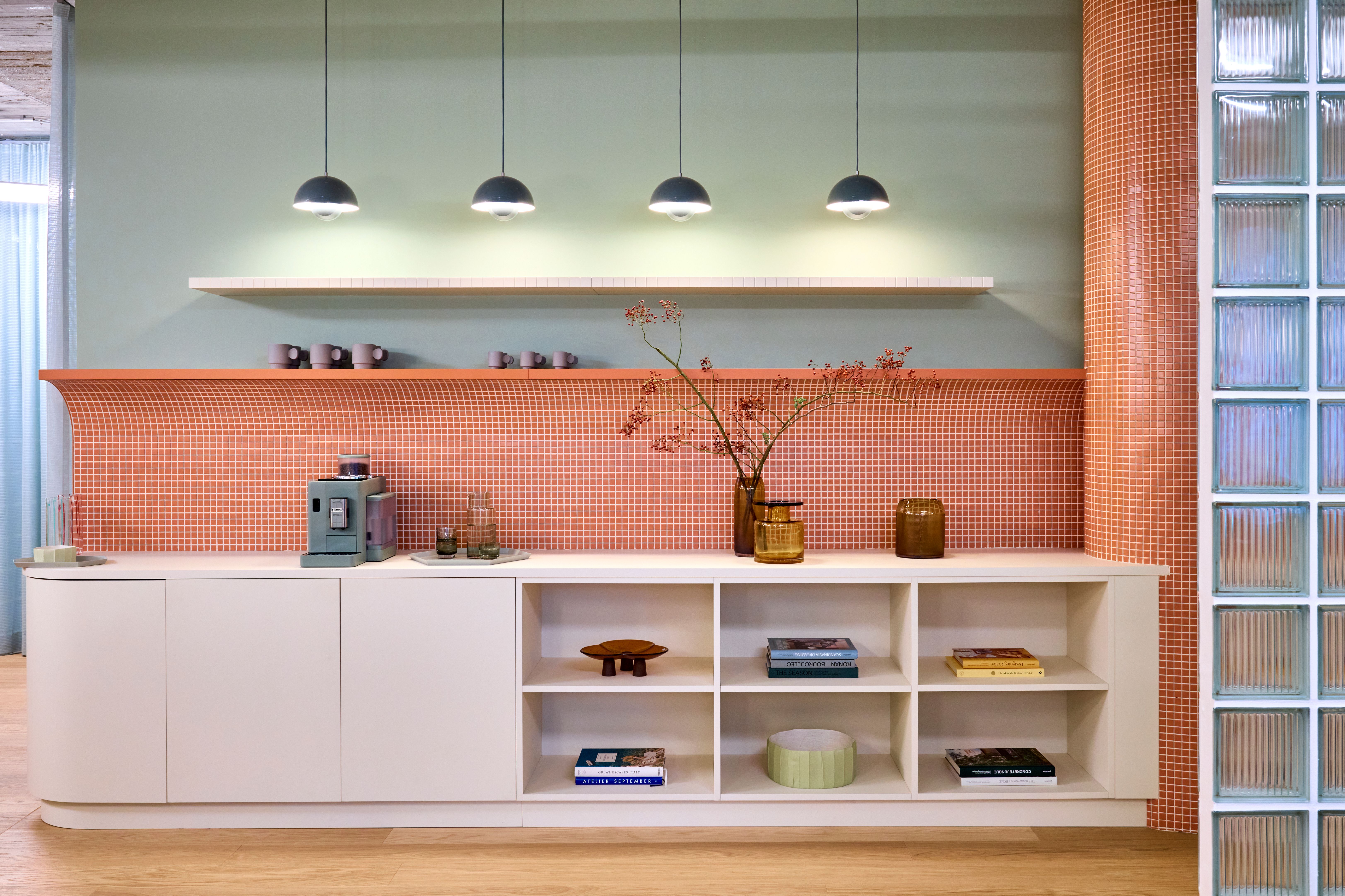 Eine farblich präzise inszenierte Praxiszone mit salbeigrüner Wand, runder Terrakotta-Mosaikverkleidung und maßgefertigter Stauraumfront zeigt den unverwechselbaren Designansatz von Stephanie Thatenhorst für „Lieblingszahnarzt“.