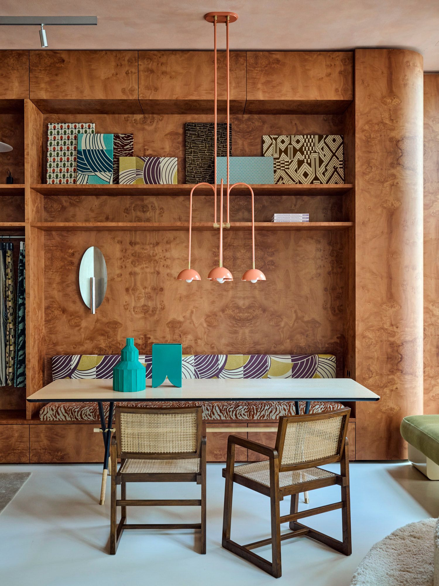 Im Showroom von Stephanie Thatenhorst treffen grafische Stoffe, warmes Holz und eine skulpturale Pendelleuchte auf einen modernen Tisch mit Geflechtstühlen.