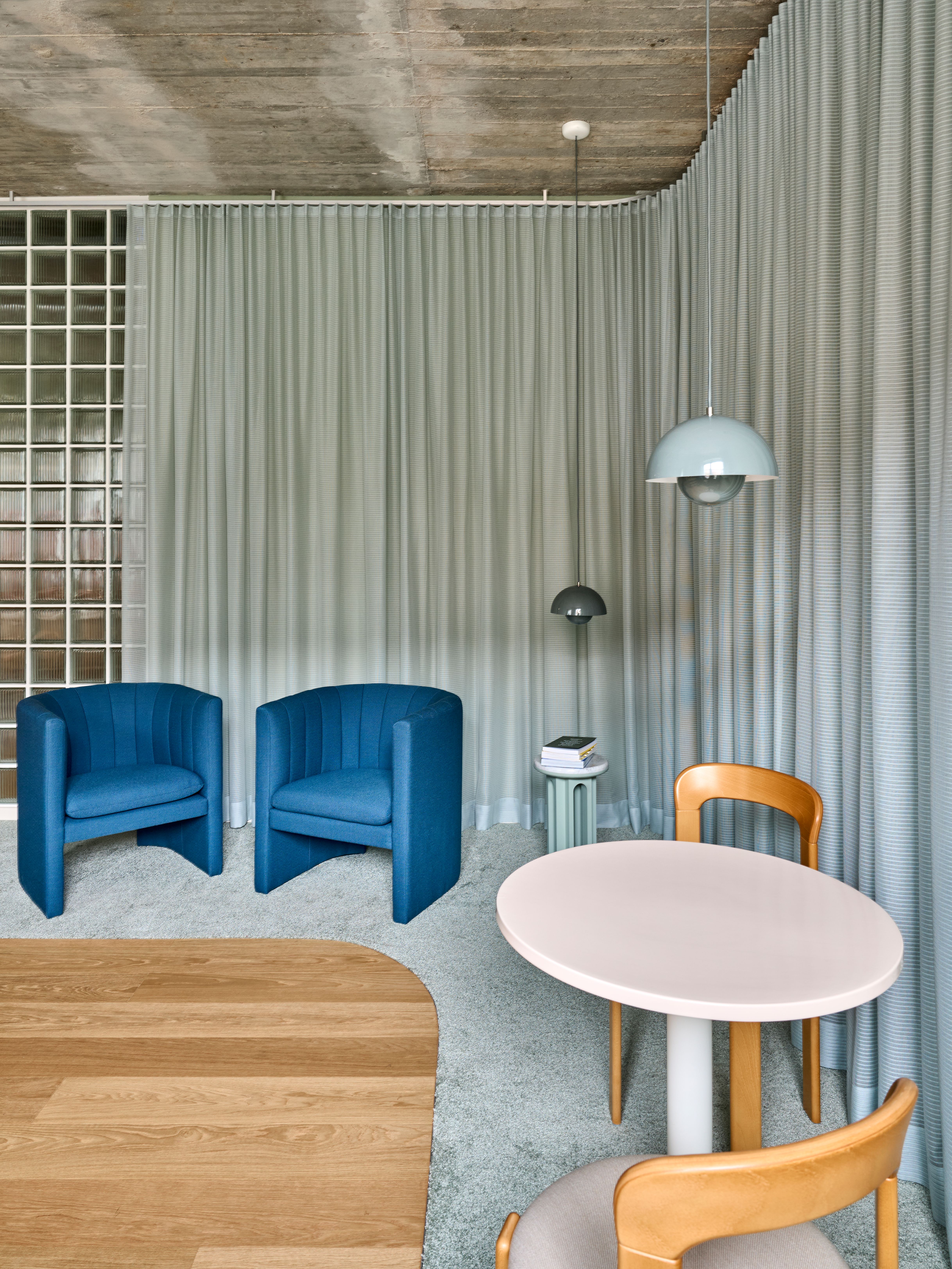 Eine ruhige Loungezone mit blauen Sesseln, textilen Vorhängen und skulpturalen Leuchten prägt die entspannte Atmosphäre in der Praxis „Lieblingszahnarzt“.