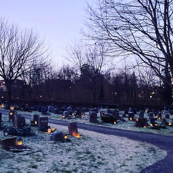 Kirkegård i skumringen med lys og snø