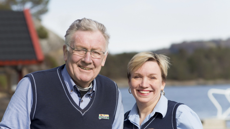 To ansatte fra Joker smiler til kamera, iført butikkuniform med Joker-logo