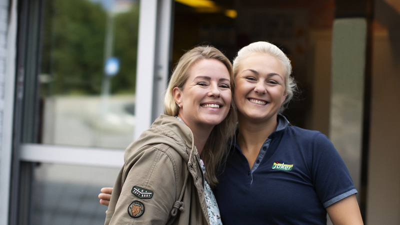 Smilende kunde og Joker-ansatt står sammen utenfor butikken
