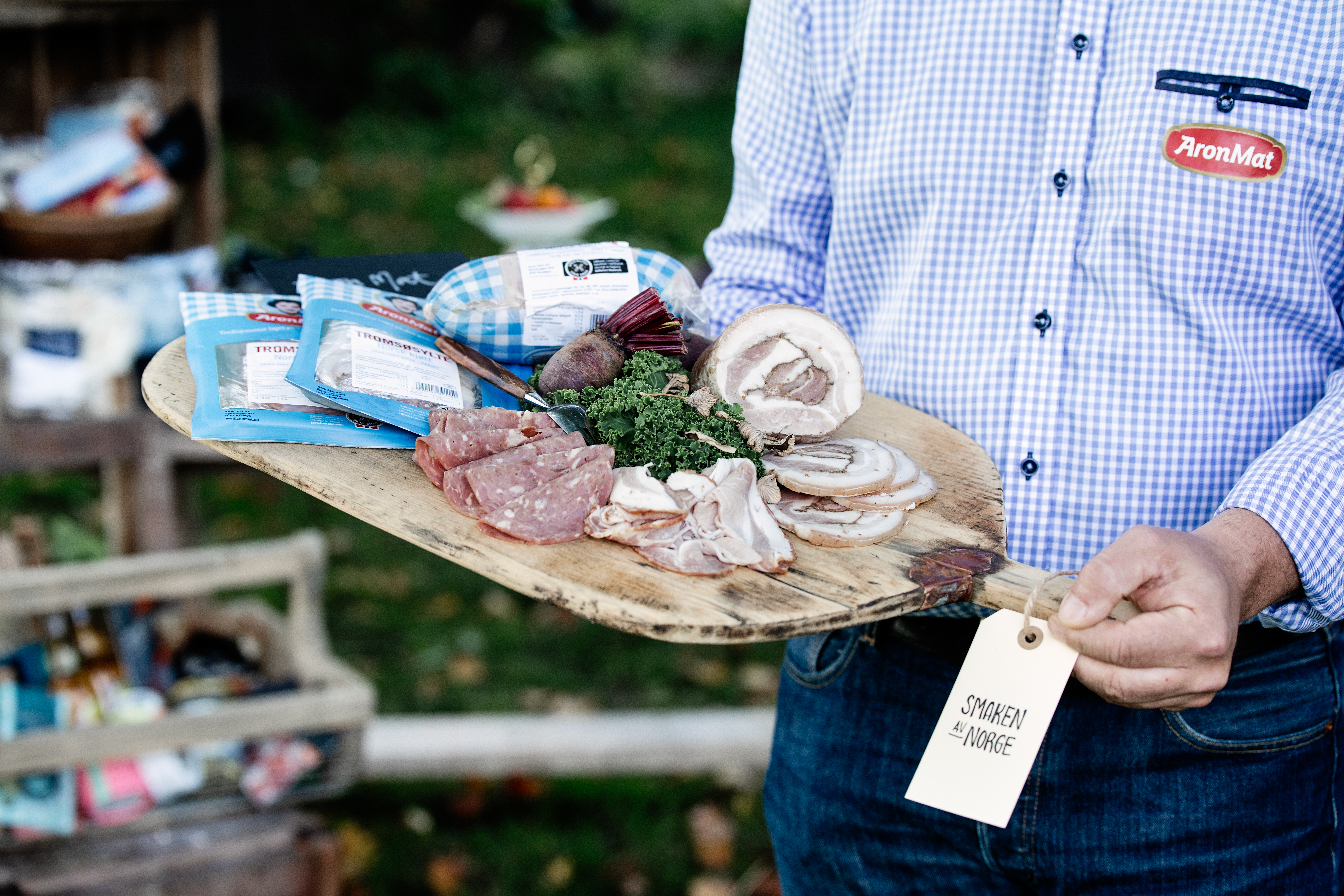 En pPerson holder et trefat med ulike kjøttprodukter fra AronMat