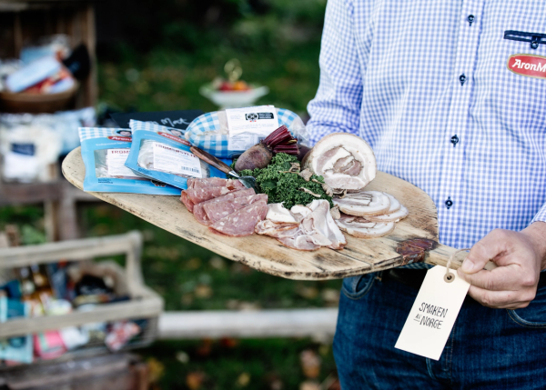 En pPerson holder et trefat med ulike kjøttprodukter fra AronMat