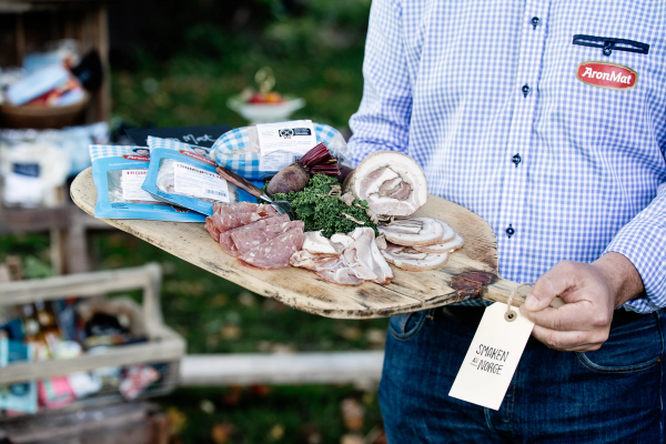 En pPerson holder et trefat med ulike kjøttprodukter fra AronMat