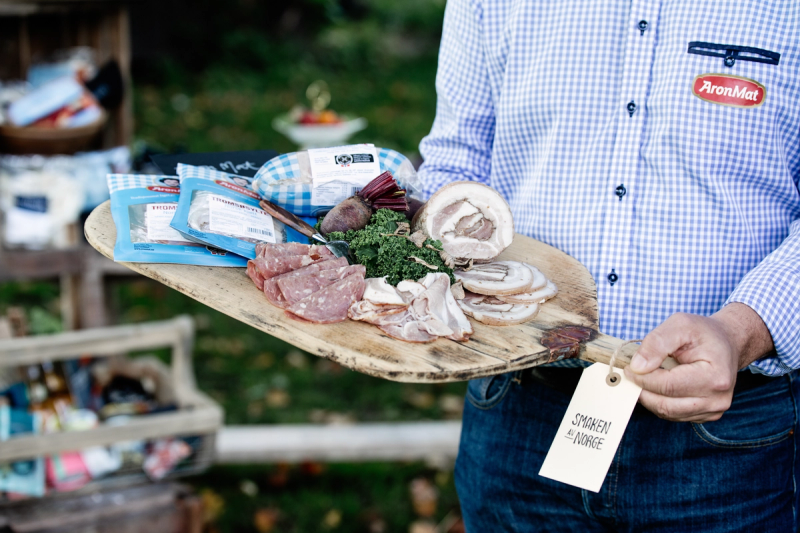 En pPerson holder et trefat med ulike kjøttprodukter fra AronMat