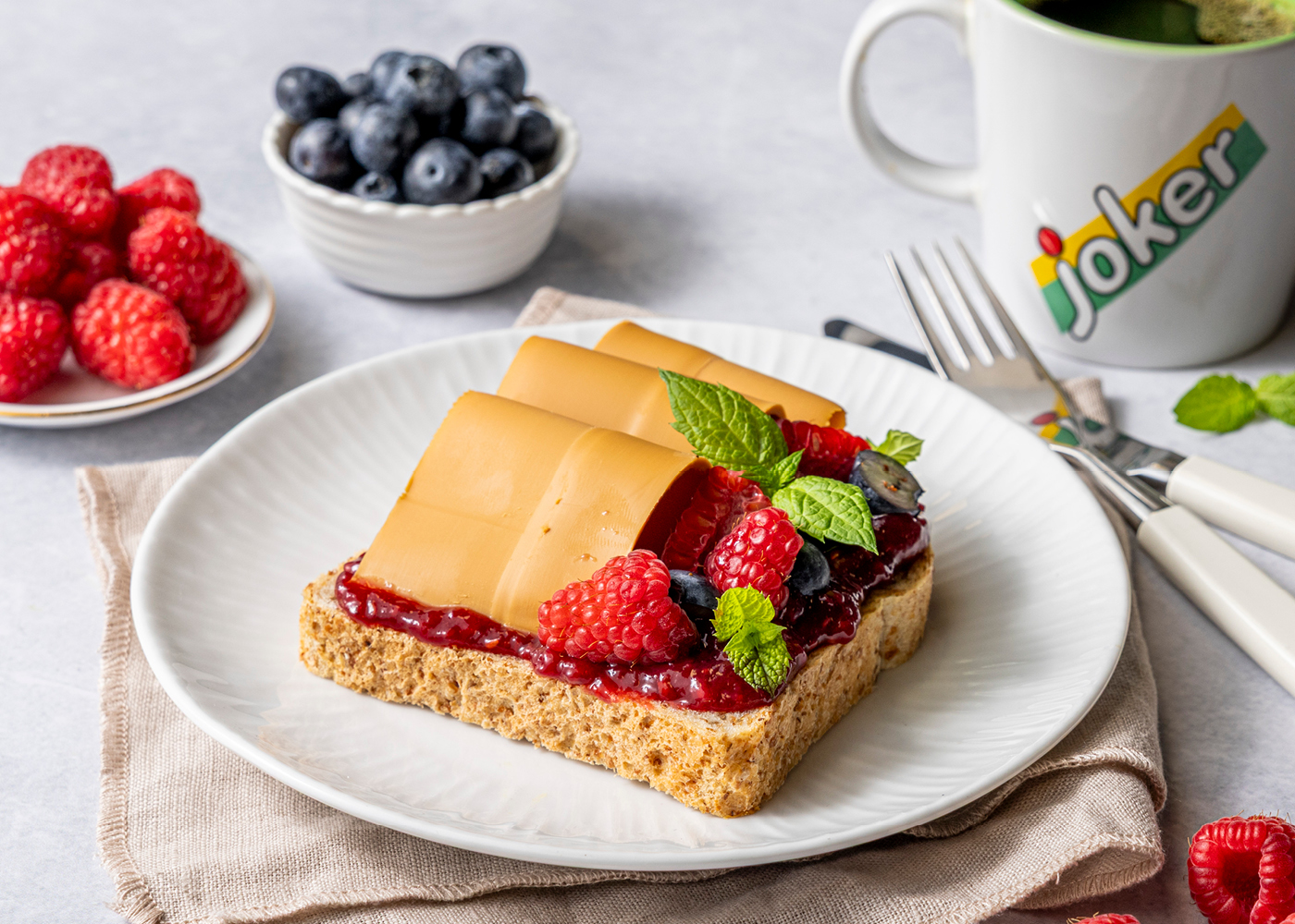 Brødskive med brunost, bringebærsyltetøy og friske bær