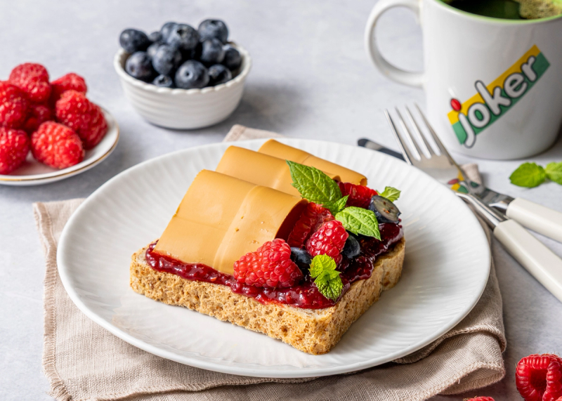 Brødskive med brunost, bringebærsyltetøy og friske bær
