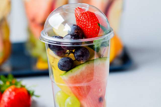 Et plastbeger fylt med vannmelon, druer, jordbær og ananas