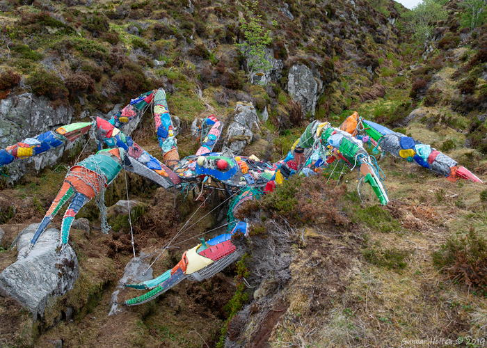 Kunstinstallasjon av en fargerik krabbe laget av plastavfall i naturen