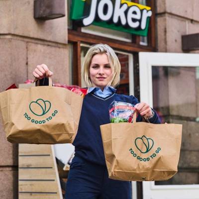 En Joker-ansatt holder frem Too Good To Go poser