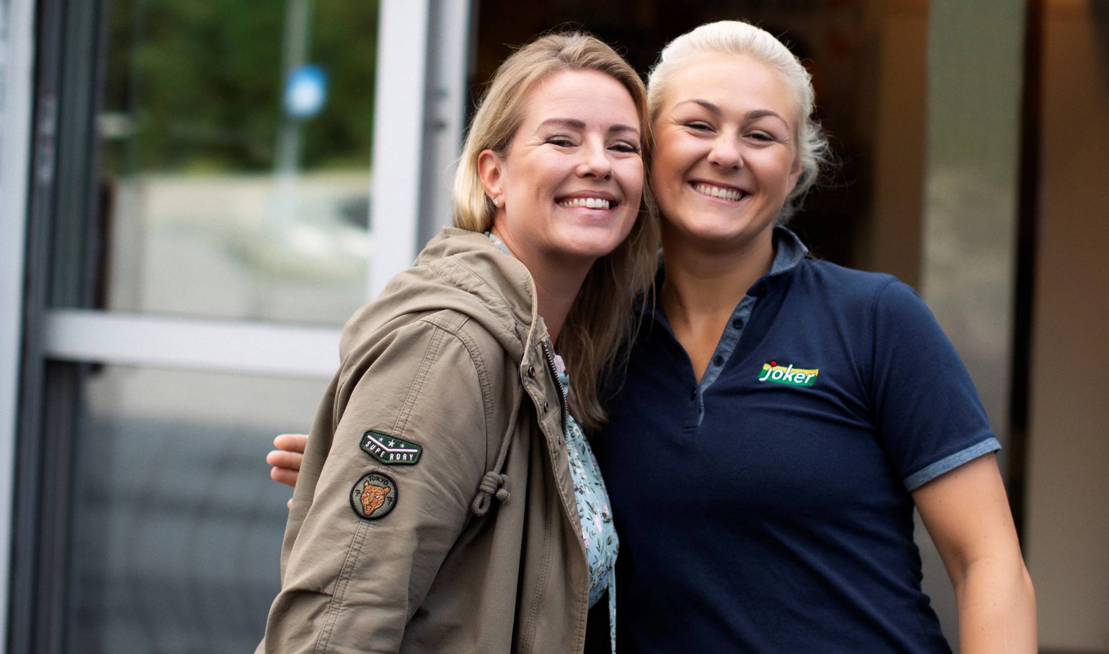 En ansatt og kunde smiler foran Joker Tinnheia