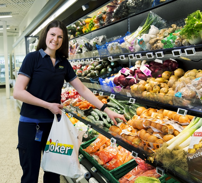 En ansatt plukker grønnsaker i frukt- og grøntavdelingen