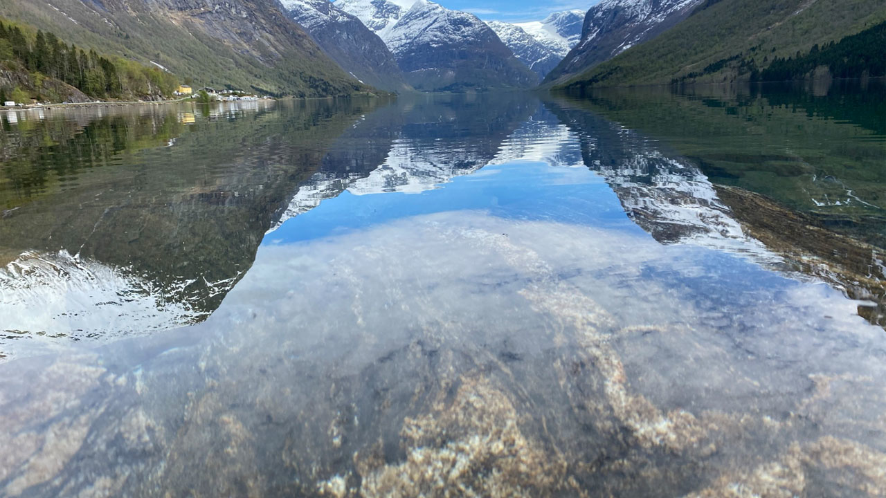 Fantastiske fjell som speiler seg i vannet