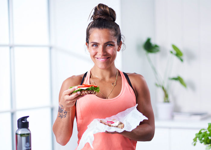 Funkygine i treningsklær smiler og holder en brødskive