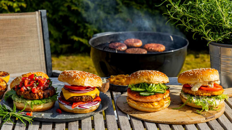 Fire forskjellige burgere med grønnsaker og ost på et bord