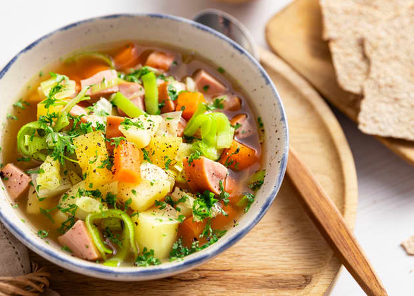Grønnsakssuppe med pølsebiter, poteter, gulrøtter og urter, servert med knekkebrød