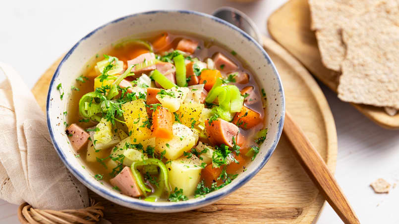 Grønnsakssuppe med pølsebiter, poteter, gulrøtter og urter, servert med knekkebrød