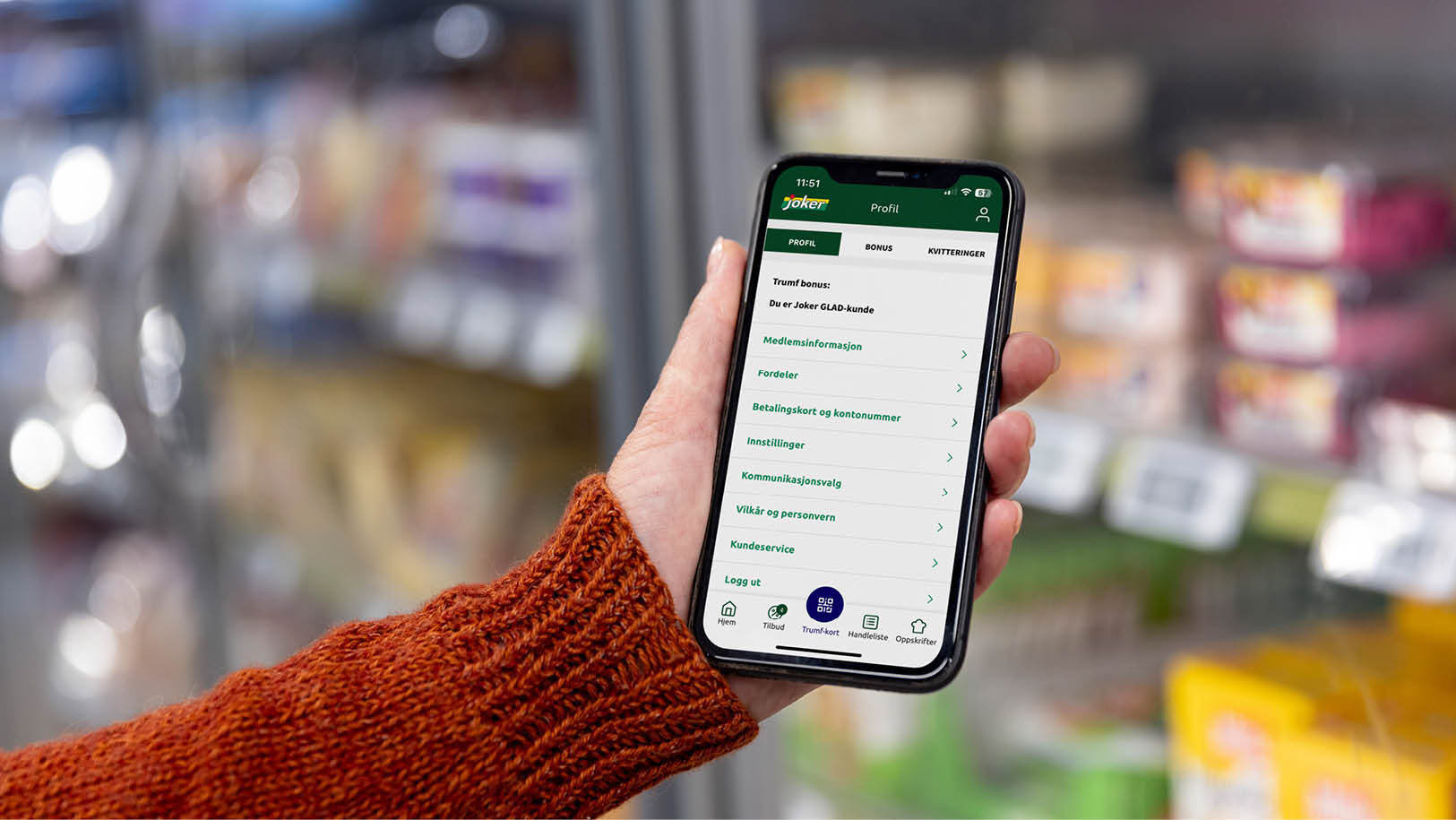 En hånd holder mobiltelefon med Joker-appen åpen i butikk