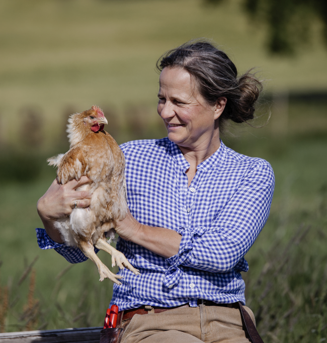 Marianne Olssøn holder en høne ute på et jorde