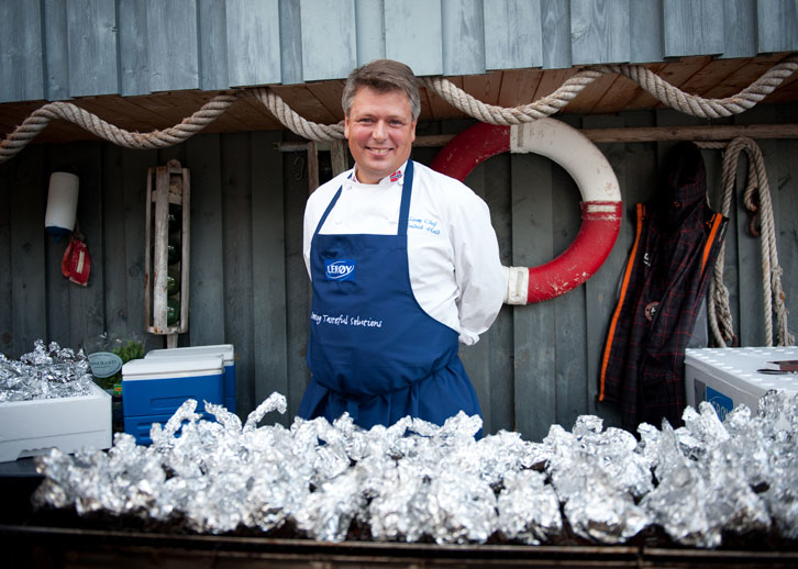 Fredrik Hald står foran en grill med mange foliepakker