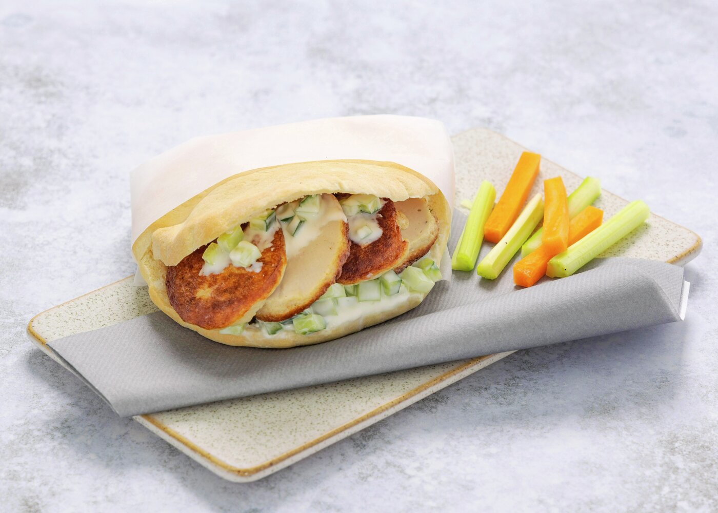 Pitabrød fylt med fiskekaker og grønnsaker, servert med staver av gulrot og selleri