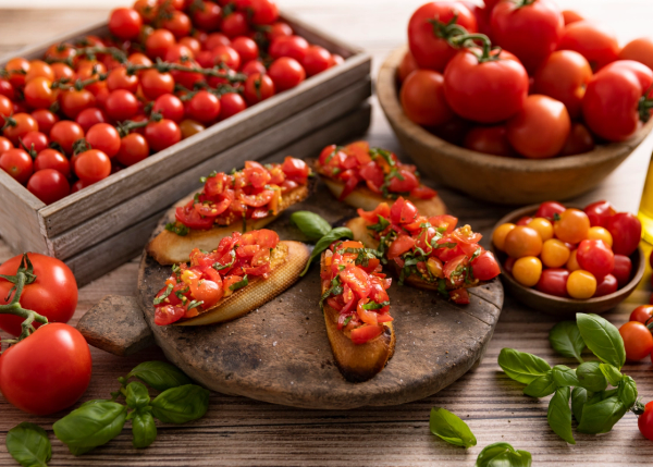 Bruschetta med tomater og basilikum, omgitt av ferske tomater i ulike farger